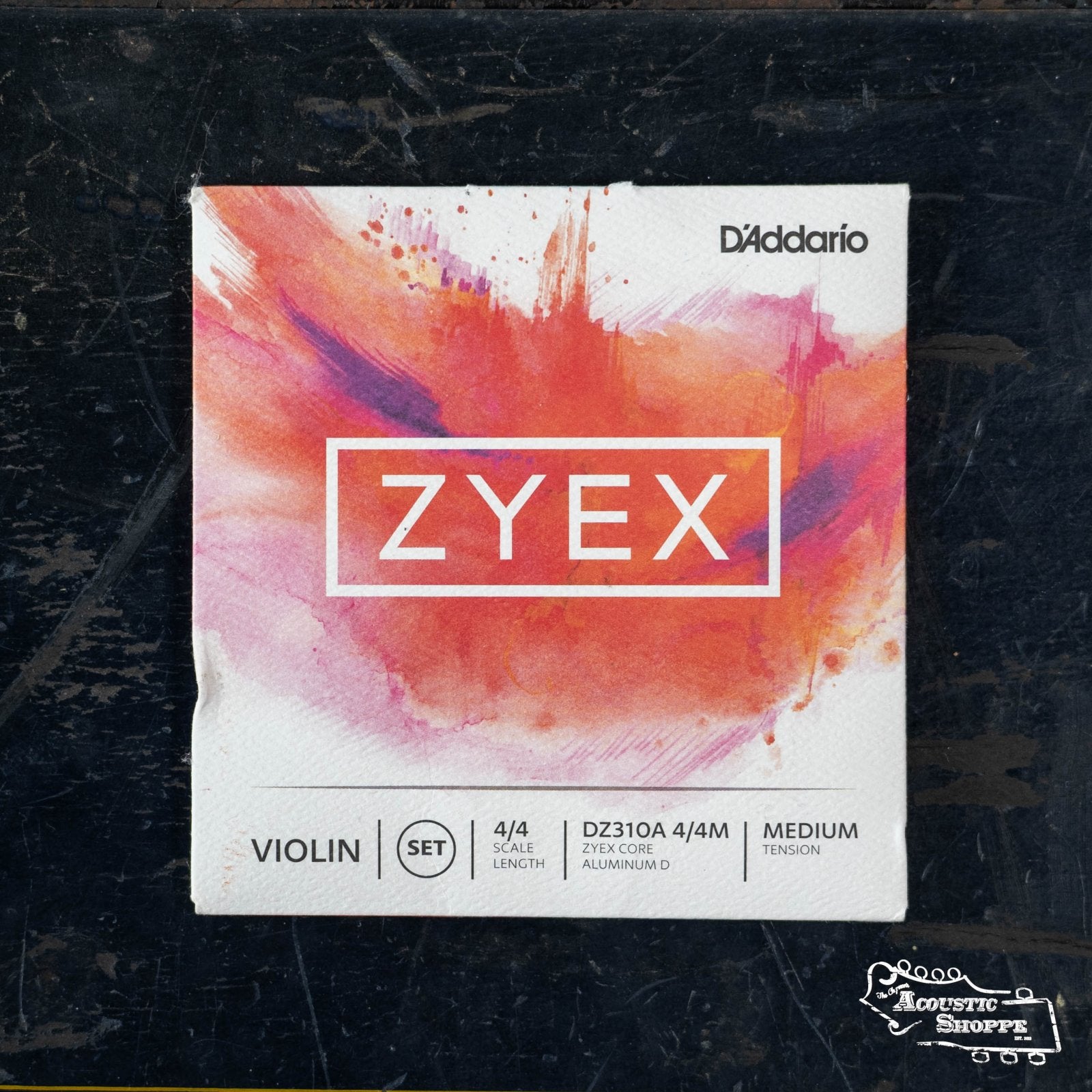 The DAddario Zyex Violin String Set with Aluminum D features a 4/4 scale, medium tension synthetic core, and comes in packaging with a white background and bold red, pink, and orange strokes.