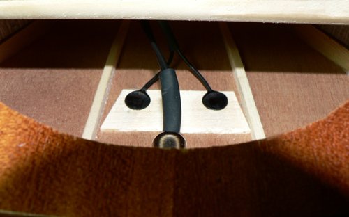 Close-up of the inside of a ukulele with a K&K Aloha Twin Ukulele Pickup by K&K Sound, featuring two black sensor discs mounted under the soundhole.