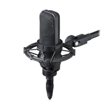 An Audio-Technica Cardioid Condenser Mic (AT4040) with a mesh grille is mounted in a shock mount on a microphone stand, shown from an angle against a plain white background.