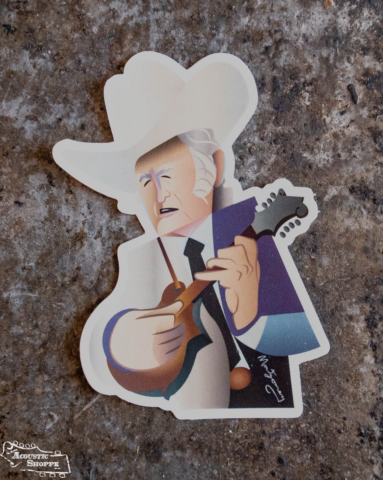 The Bill Monroe Sticker by Mark A Montgomery from The Acoustic Shoppe features a cartoon-style older man with white hair and a cowboy hat playing mandolin on a brown textured background with a small white signature.