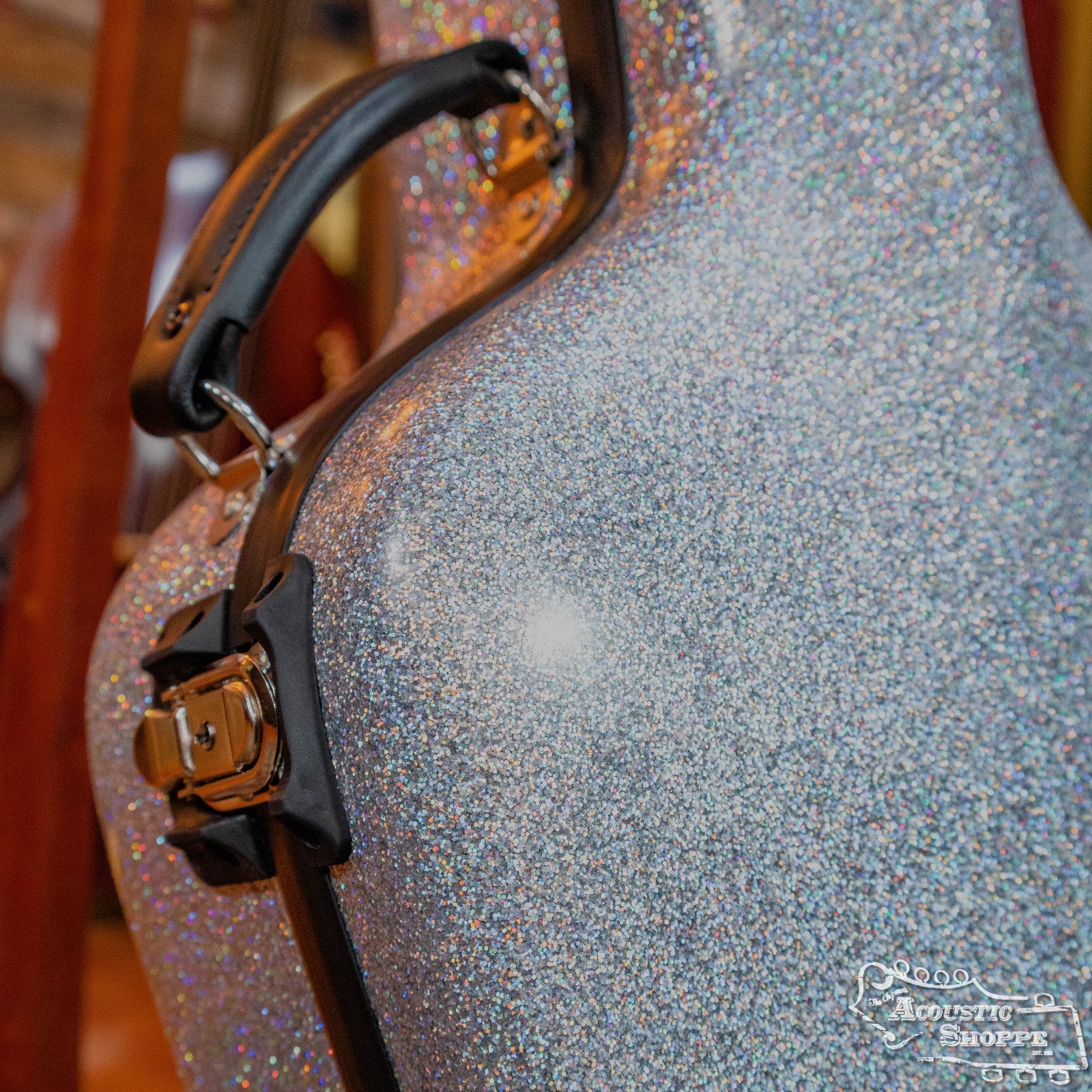 A close-up of the Calton Cases Dreadnought D-18 Diamond Smooth Glitter case (#21-1800007) shows its sparkling silver exterior, black handle, chrome latches, and the Acoustic Shoppe logo in the lower right corner.