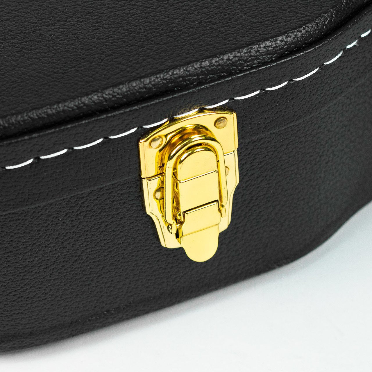 Close-up of a gold latch on the Guardian CG-044-D Hardshell Case-Vintage Dreadnought by Guardian, featuring black textured exterior with white stitching, resting on a white surface.