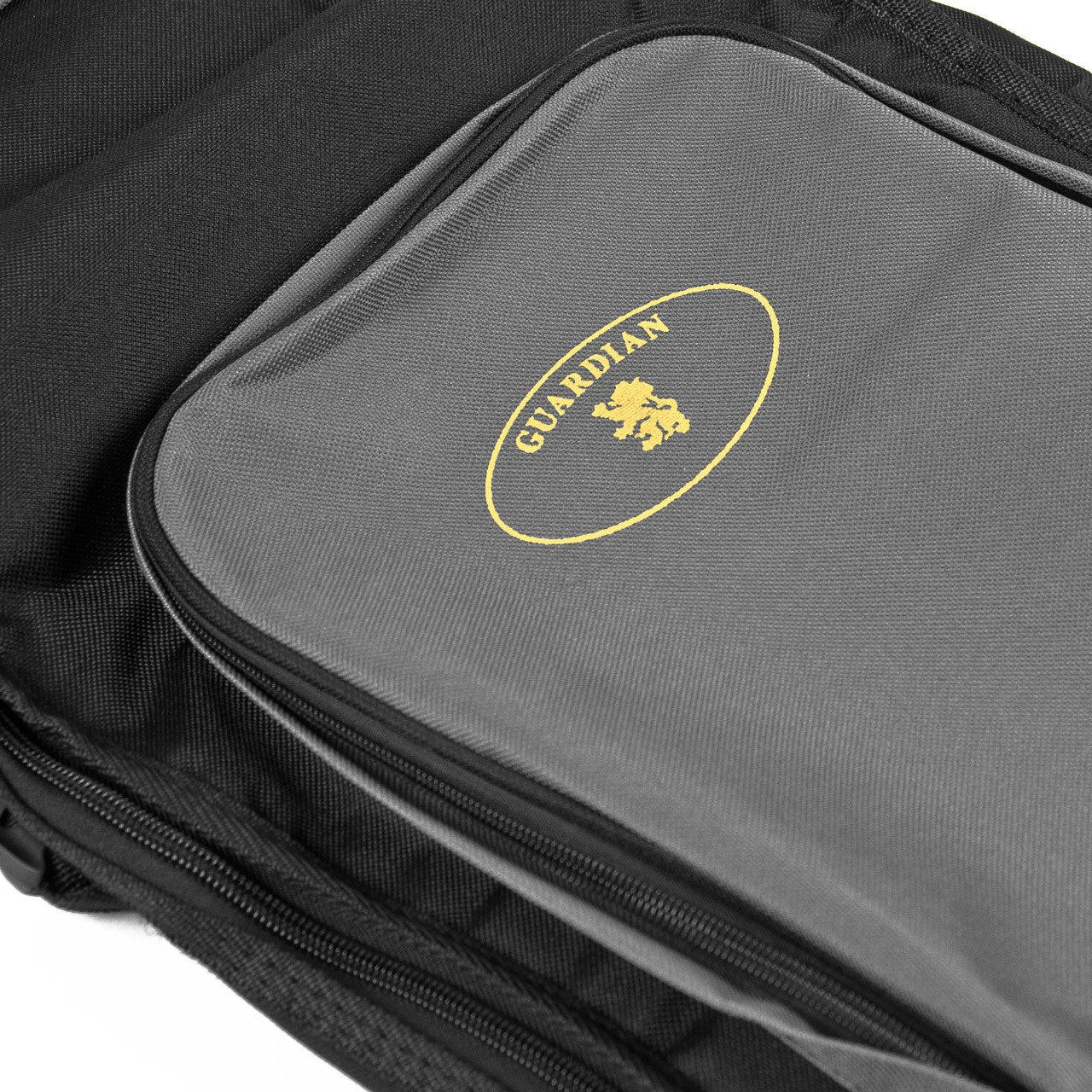 A close-up shows the Guardian CG-205-O Guitar Bag’s gray pocket with a yellow “GUARDIAN” logo and lion emblem, contrasted against the black Duraguard exterior of this padded 0-size guitar case.