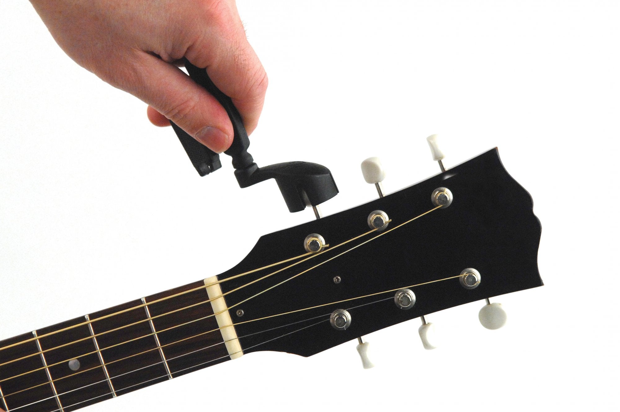 A hand uses the D'Addario Pro-Winder String Winder and Cutter - Black to tune a guitar by turning one of the tuning pegs on the headstock.