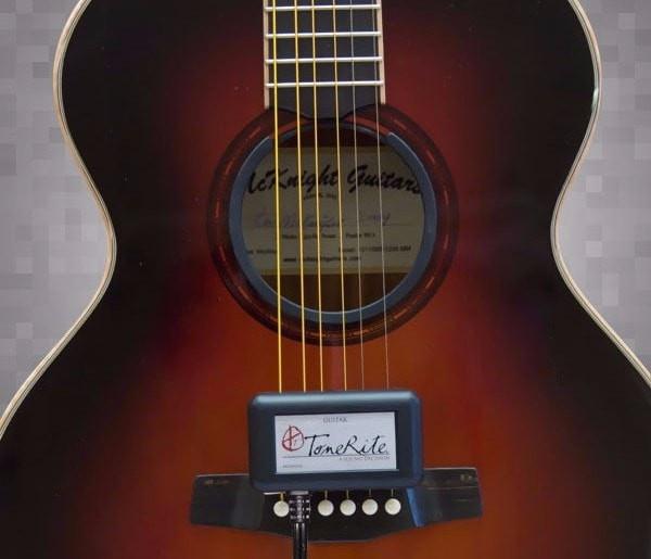 Close-up of the ToneRite Guitar by The Acoustic Shoppe attached to an acoustic guitar, accelerating the play-in process and enhancing tone—ideal for vintage instruments.