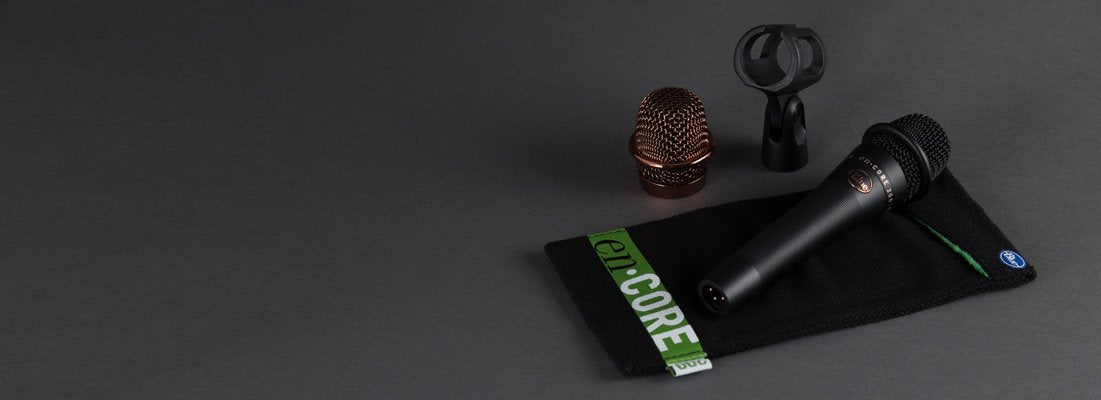 A Blue Encore 200 Dynamic Microphone by Blue Microphones with a copper grille, black pouch labeled en:CORE, and a black clip are shown on a dark gray surface.