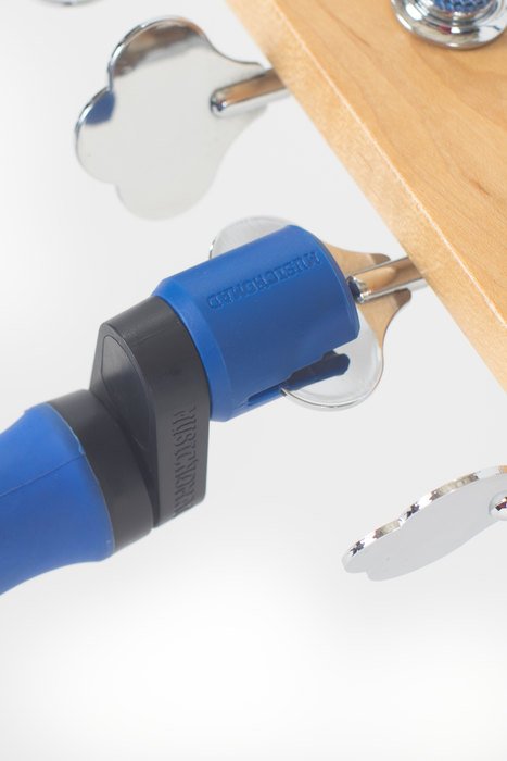 A Music Nomad Grip Winder (MN221) is tightening a screw on the metal tuner of a wooden guitar headstock.