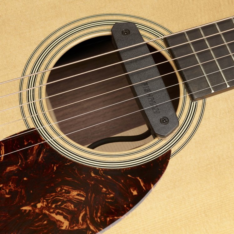 Close-up of an acoustic guitar’s soundhole with a Fishman Neo-D Humbucking Pickup (Pro-Neo-D02) installed, displaying the strings, light wood body, and dark marbled pickguard for enhanced clarity. Brand: Fishman.