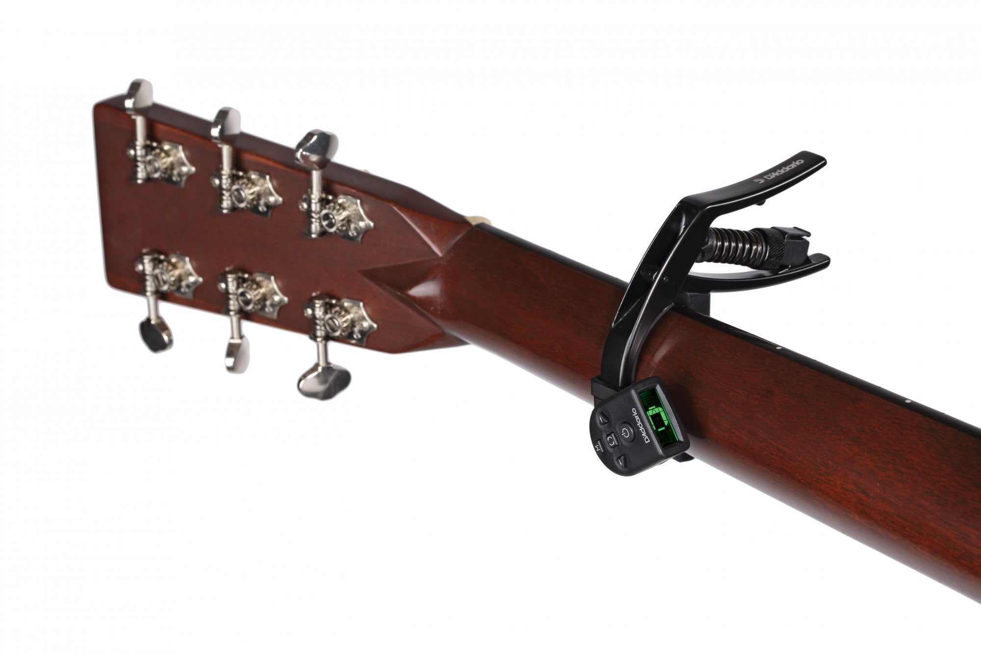 Close-up of a guitar neck with metal tuning pegs, a DAddario NS Artist Capo PW-CP-10 featuring micrometer tension adjustment clamped to the fretboard, and an electronic tuner displaying a green screen.