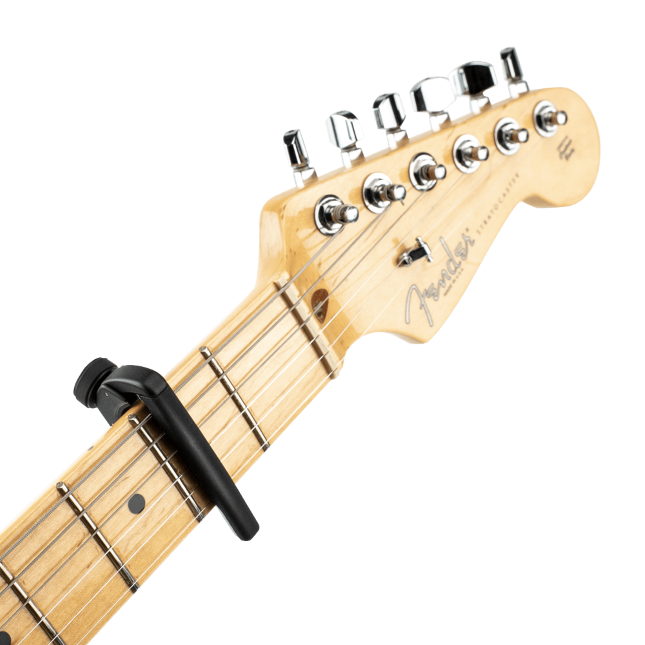 Close-up of a guitar headstock and upper neck with a D'Addario Pro Plus Guitar Capo - Silver, featuring FlexFit technology, attached at the first fret. The tuning pegs are clearly visible.