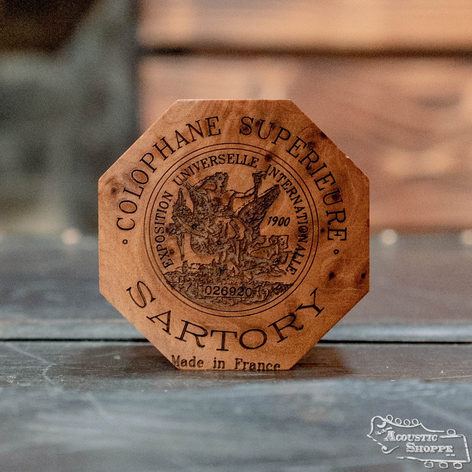 Octagonal wooden box labeled Sartory Rosin by Sartory, made in France, features an engraved woman and horse. The box rests on a rustic wooden surface.
