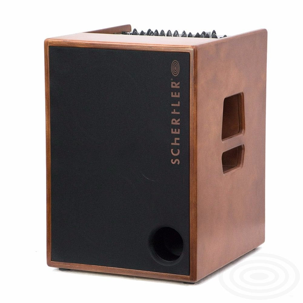 A wooden floor model Schertler Amp ROY by AER The Acoustic People features a black front panel with side handles, a circular bass port, and vertically printed branding—ideal as a 400W amplifier for acoustic instruments.