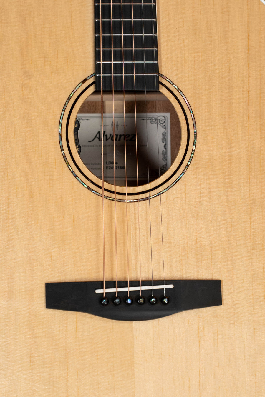Close-up of an Alvarez Laureate Series LD60e Sitka/Mahogany Dreadnought Guitar w/LR Baggs Hifi Pickup, showing the strings, decorative soundhole inlay, part of the fretboard, and visible Alvarez label inside.