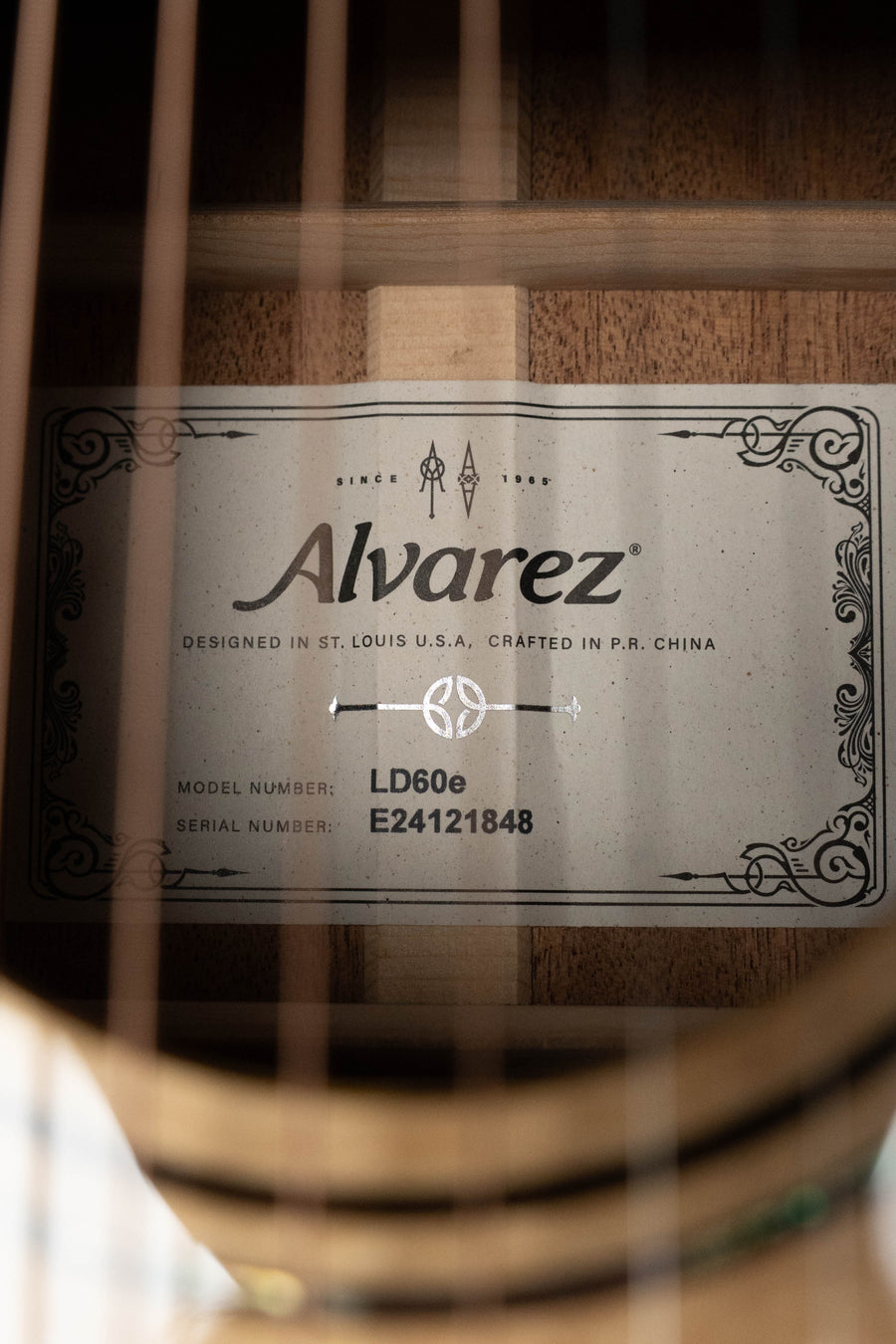 Close-up of the Alvarez Laureate Series LD60e Sitka/Mahogany Dreadnought Guitar w/LR Baggs Hifi Pickup #1848 label inside the sound hole, model LD60e, designed in St. Louis and crafted in China.