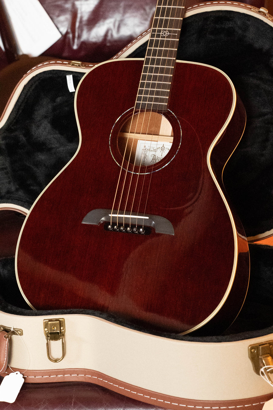 An Alvarez Yairi Honduran Series FYM66HD All Vintage OM Acoustic Guitar #7595 by Alvarez, with a glossy dark brown finish and six strings, rests inside an open plush-lined hard case with tan edges and gold hardware.