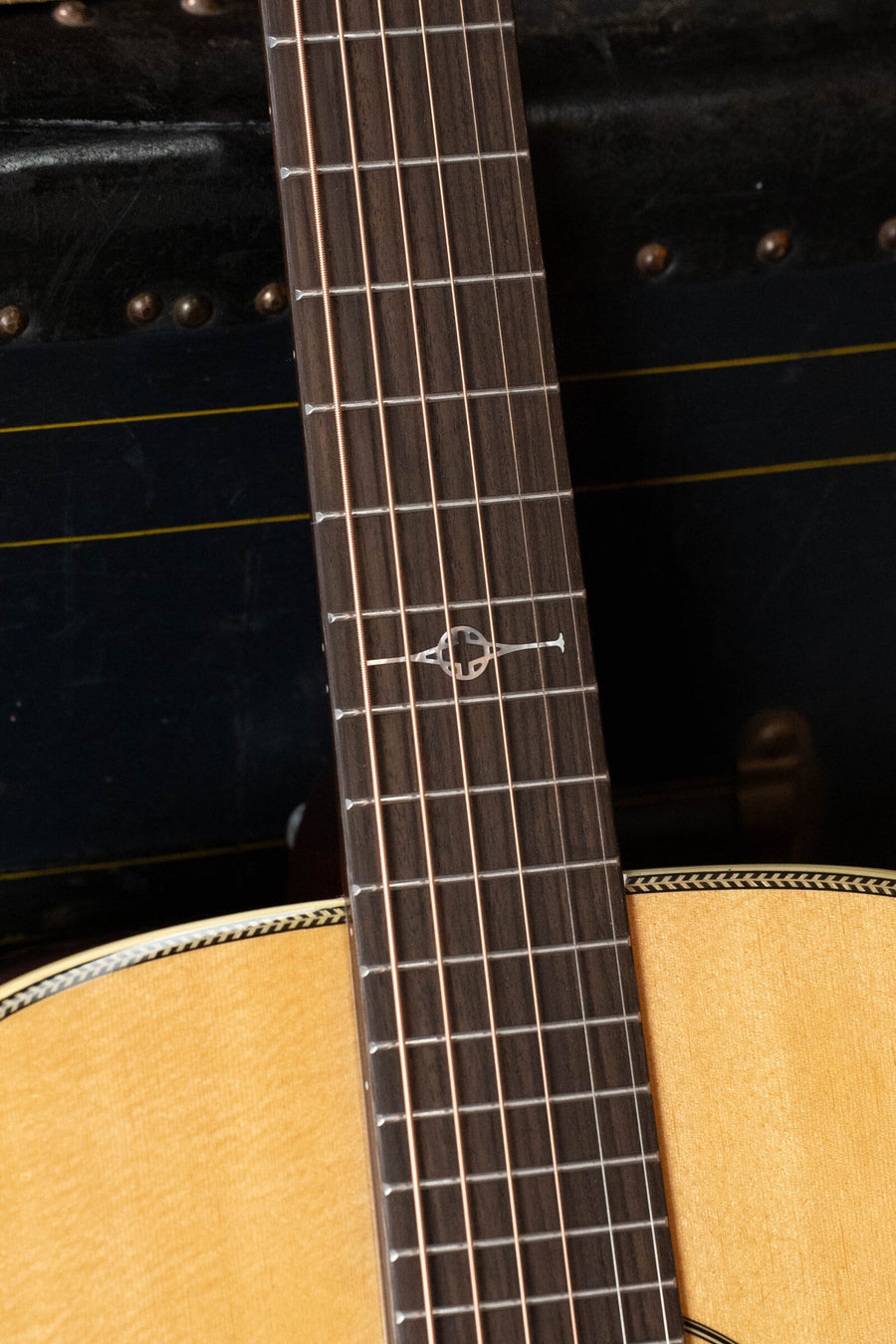 A close-up of the Alvarez Masterworks Series MF60 Herringbone Sitka/African Mahogany Orchestra Model Acoustic Guitar #2407 highlights its fretboard and body. The fretboard features a distinctive inlay at the 12th fret, while the guitar showcases a light Sitka spruce top with herringbone binding and African mahogany back and sides.