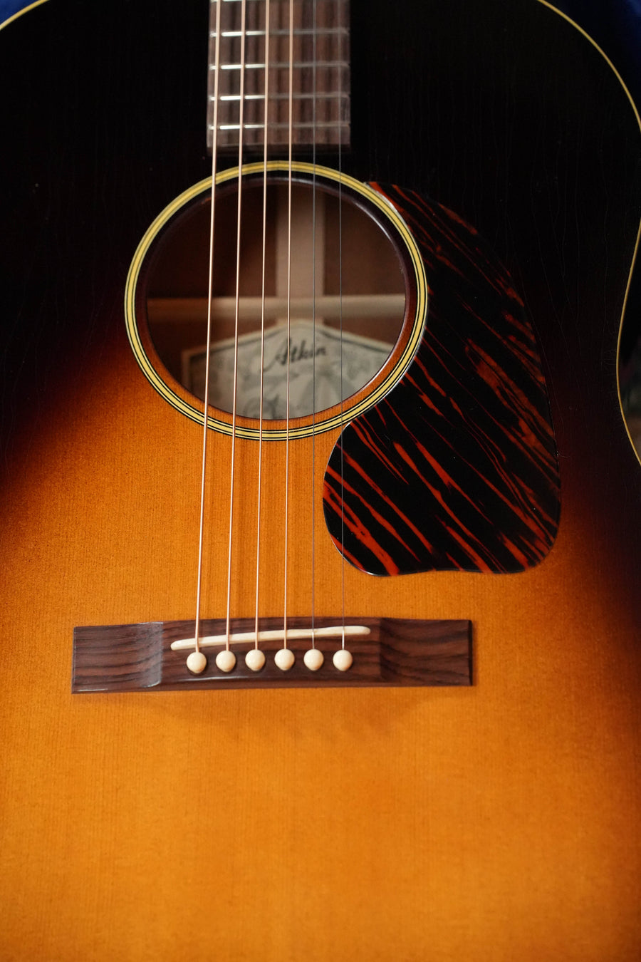Close-up of the Atkin J43 Baked Sitka/Mahogany Heavy Aged Slope Shoulder Dreadnought Acoustic Guitar #4397 by Atkin Guitars, showcasing its strings, labeled soundhole, wood grain, aged nitro finish, and patterned pickguard.