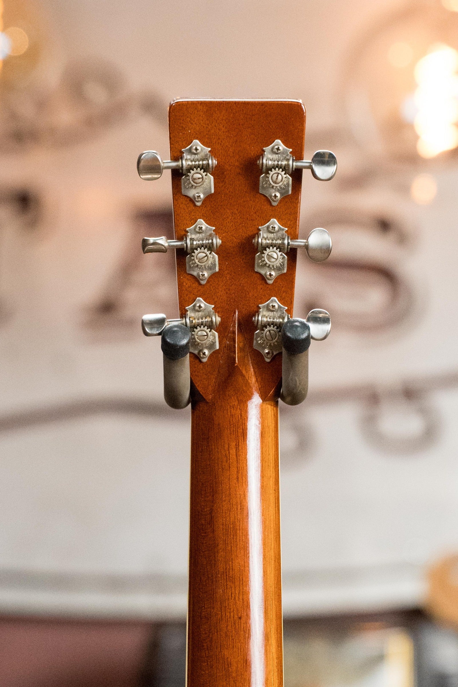 Close-up of the Atkin White Rice Baked Sitka/Rosewood Dreadnought Acoustic Guitar #3497 by Atkin Guitars, featuring an Indian rosewood headstock with six silver tuning pegs and ornate metal plates in warm, soft lighting.