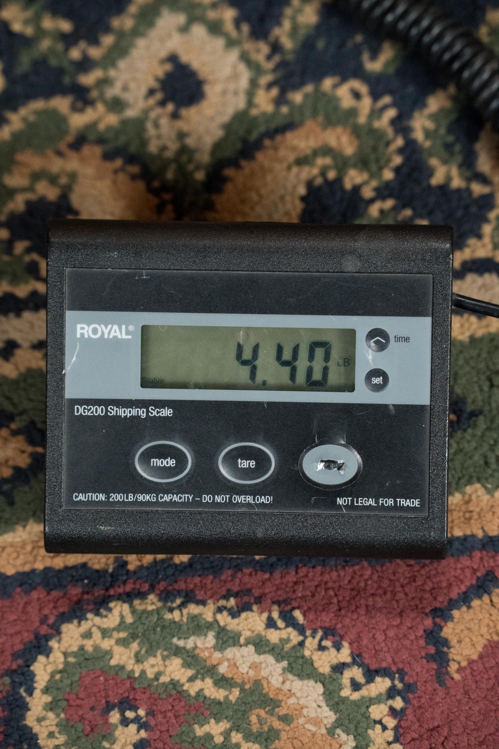 A Royal DG200 digital shipping scale on patterned carpet shows 4.40 lbs—ideal for shipping the Atkin White Rice Baked Sitka/Rosewood Dreadnought Acoustic Guitar #3497 by Atkin Guitars or a prized vintage tone guitar.