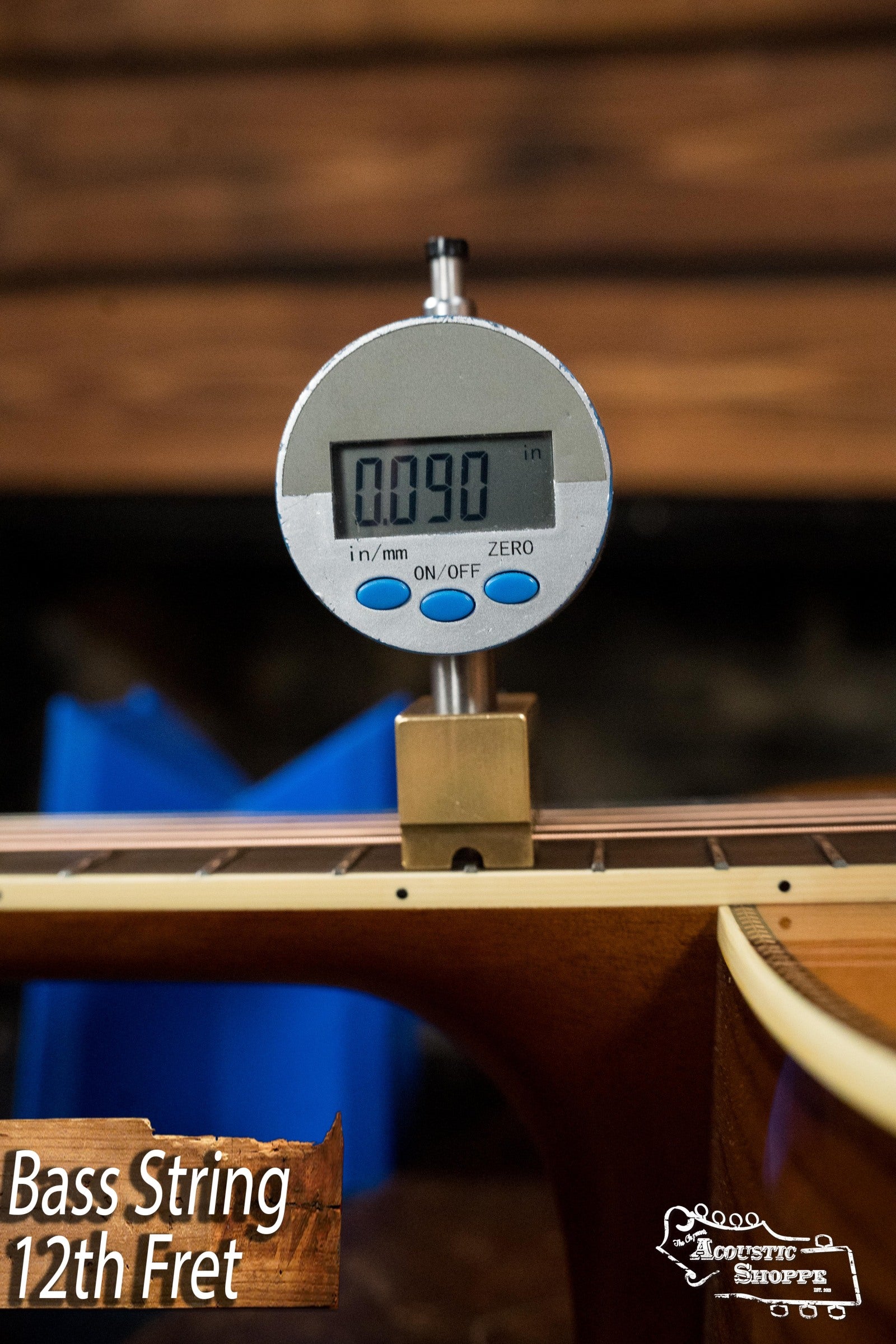 A digital gauge measures a bass string’s height at the 12th fret on an Atkin Guitars White Rice Baked Sitka/Rosewood Dreadnought Acoustic Guitar #3497, displaying 0.090. Close-up of neck shows Bass String 12th Fret text in lower left corner.