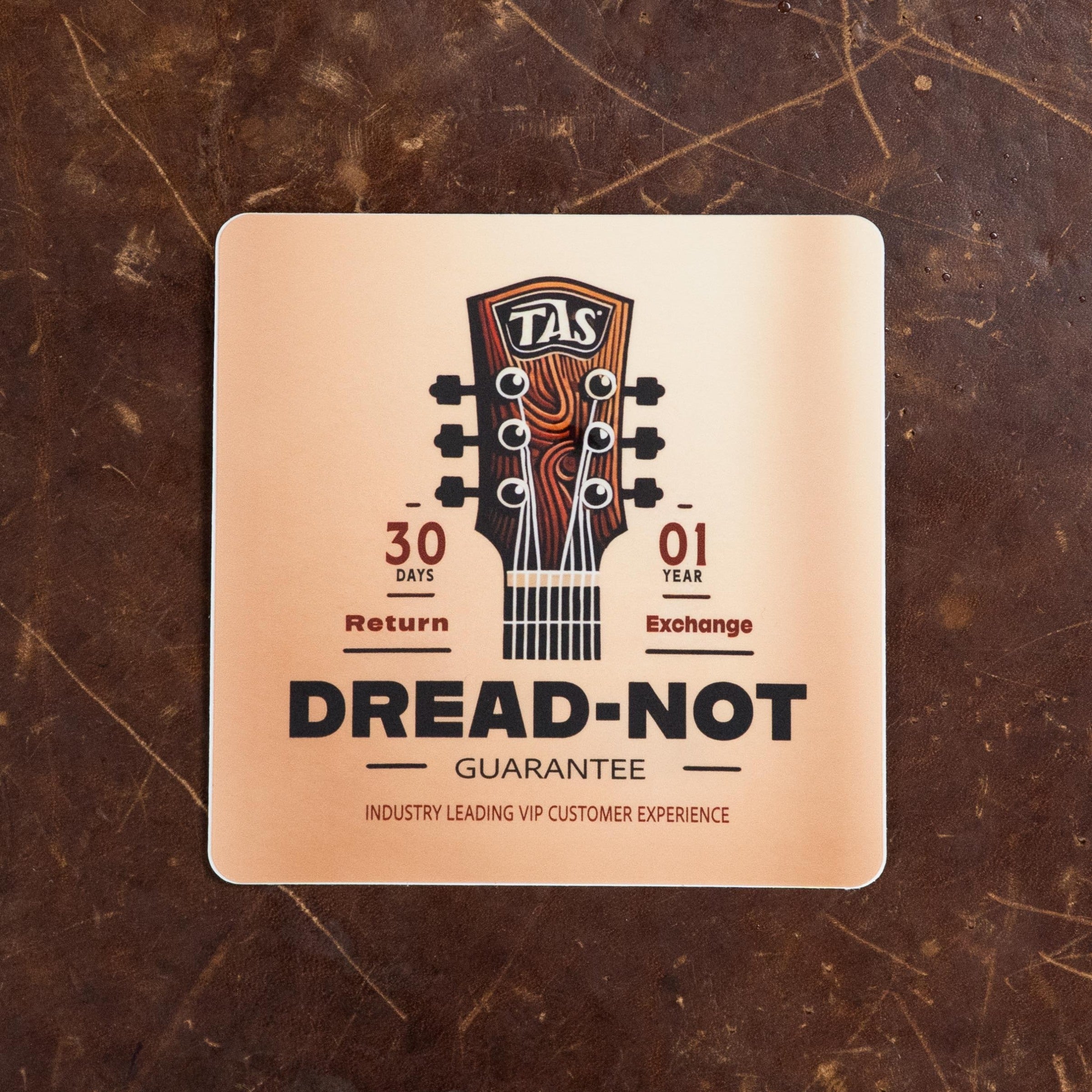 A square brown leather card displays a guitar headstock and features: 30 Days Return, 1 Year Exchange, Dread-Not Guarantee, Industry Leading VIP Service—perfect for your Atkin Guitars White Rice Baked Sitka/Rosewood Dreadnought #3497.
