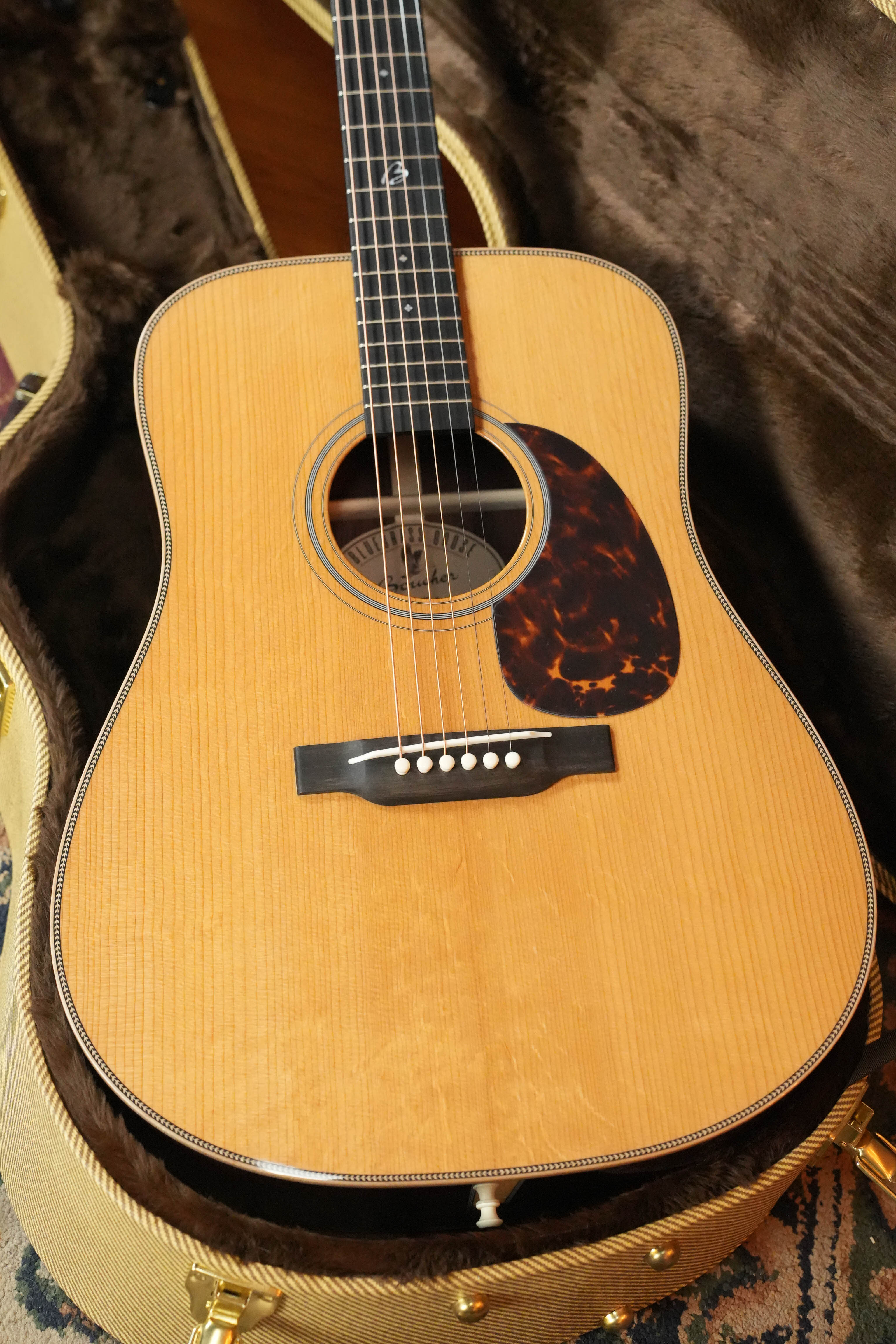 The Boucher BG-152-G Adirondack/Rosewood Bluegrass Goose Dreadnought Acoustic Guitar #1098 by Boucher Guitars, with its natural finish, Adirondack red spruce top, tortoiseshell-style pickguard, and white bridge pins, is perfect for bluegrass fans.