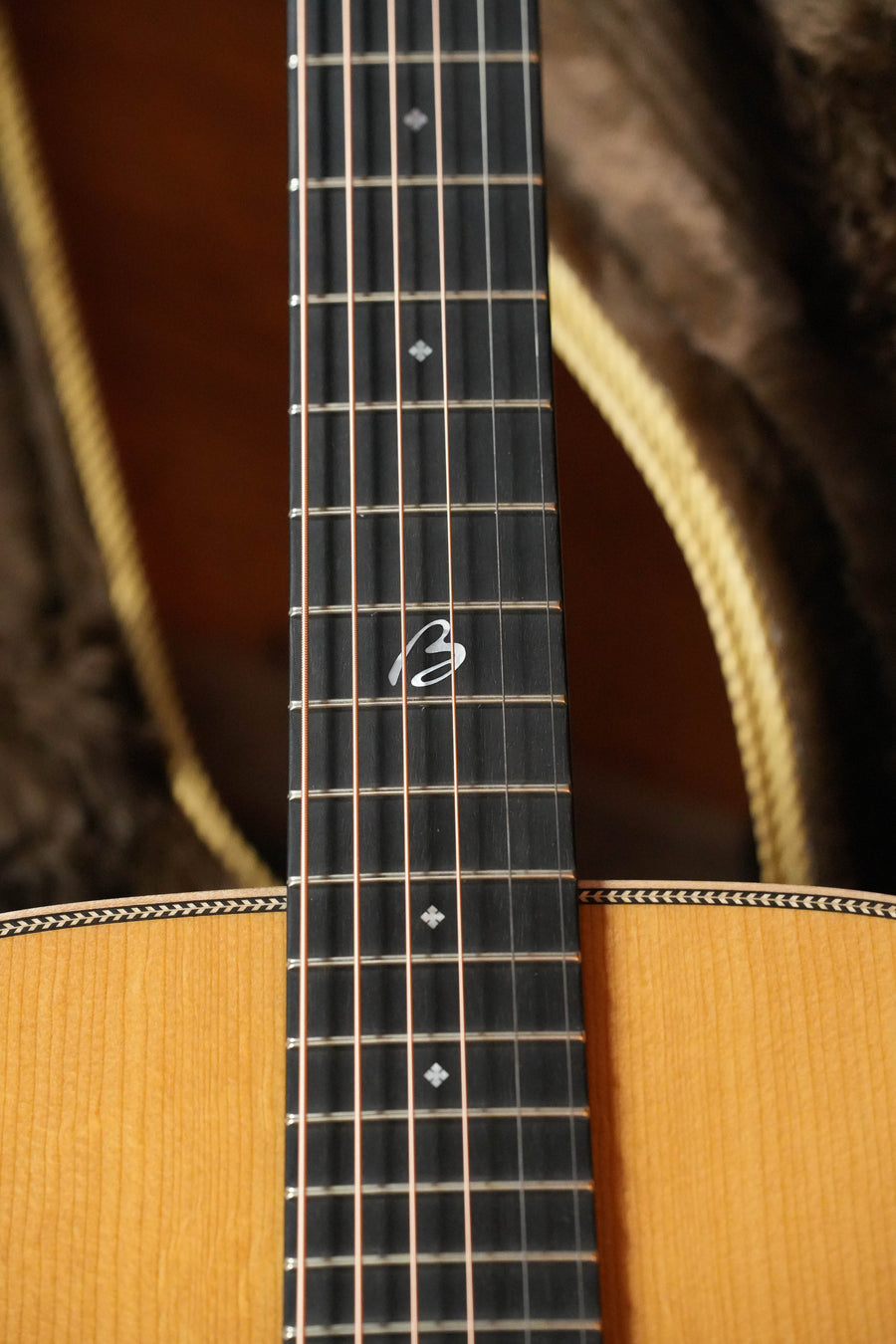A close-up of the Boucher BG-152-G Adirondack/Rosewood Bluegrass Goose Dreadnought #1098 by Boucher Guitars shows its metal frets, diamond inlays, unique 12th-fret inlay, light wood Adirondack spruce body, and detailed edge binding.
