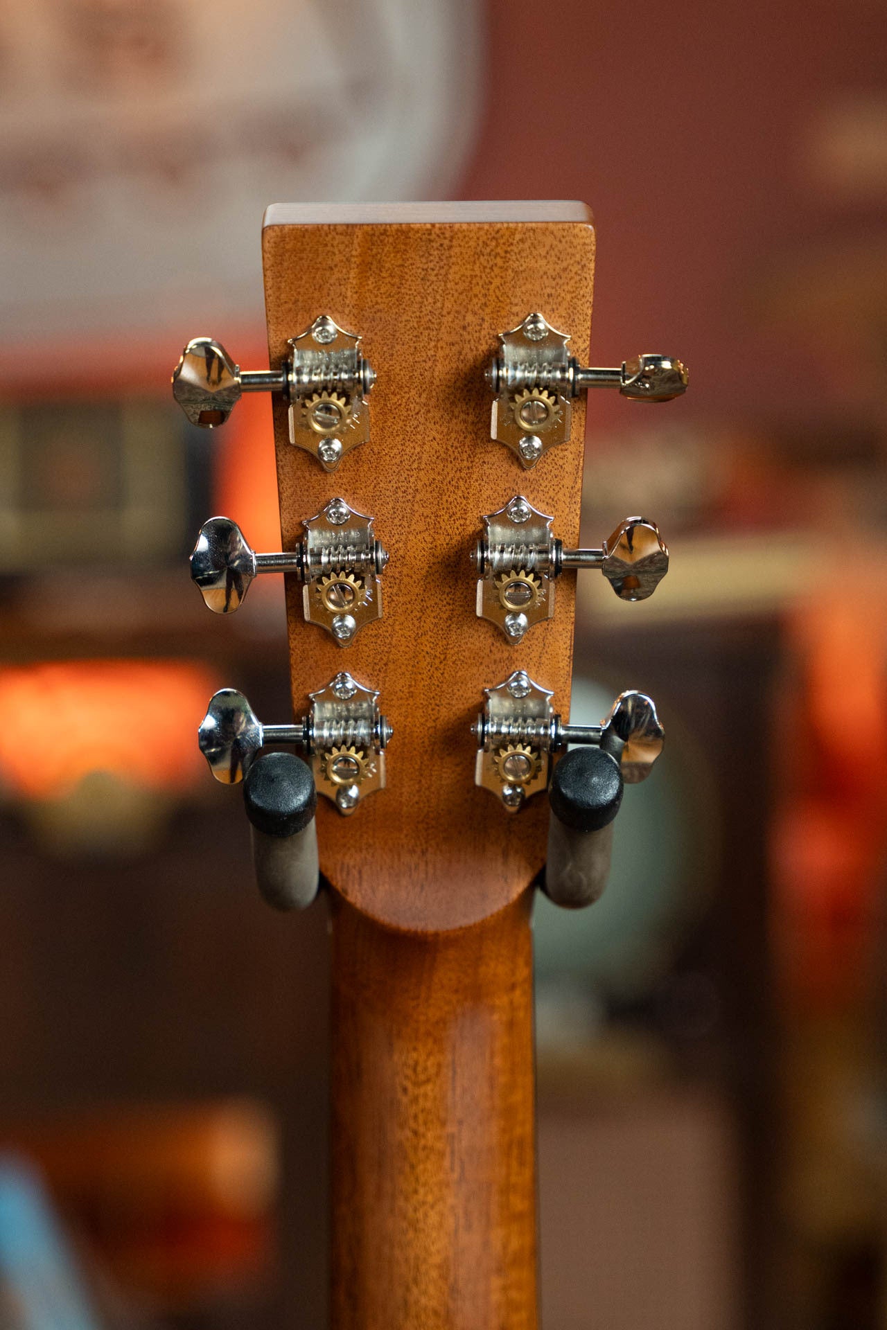 Close-up of the Boucher Guitars BG-42T-G Bluegrass Goose Series Torrefied Master Grade Adirondack/Mahogany Dreadnought #1035 headstock, featuring six metal tuning pegs against a warmly lit, blurred indoor background.