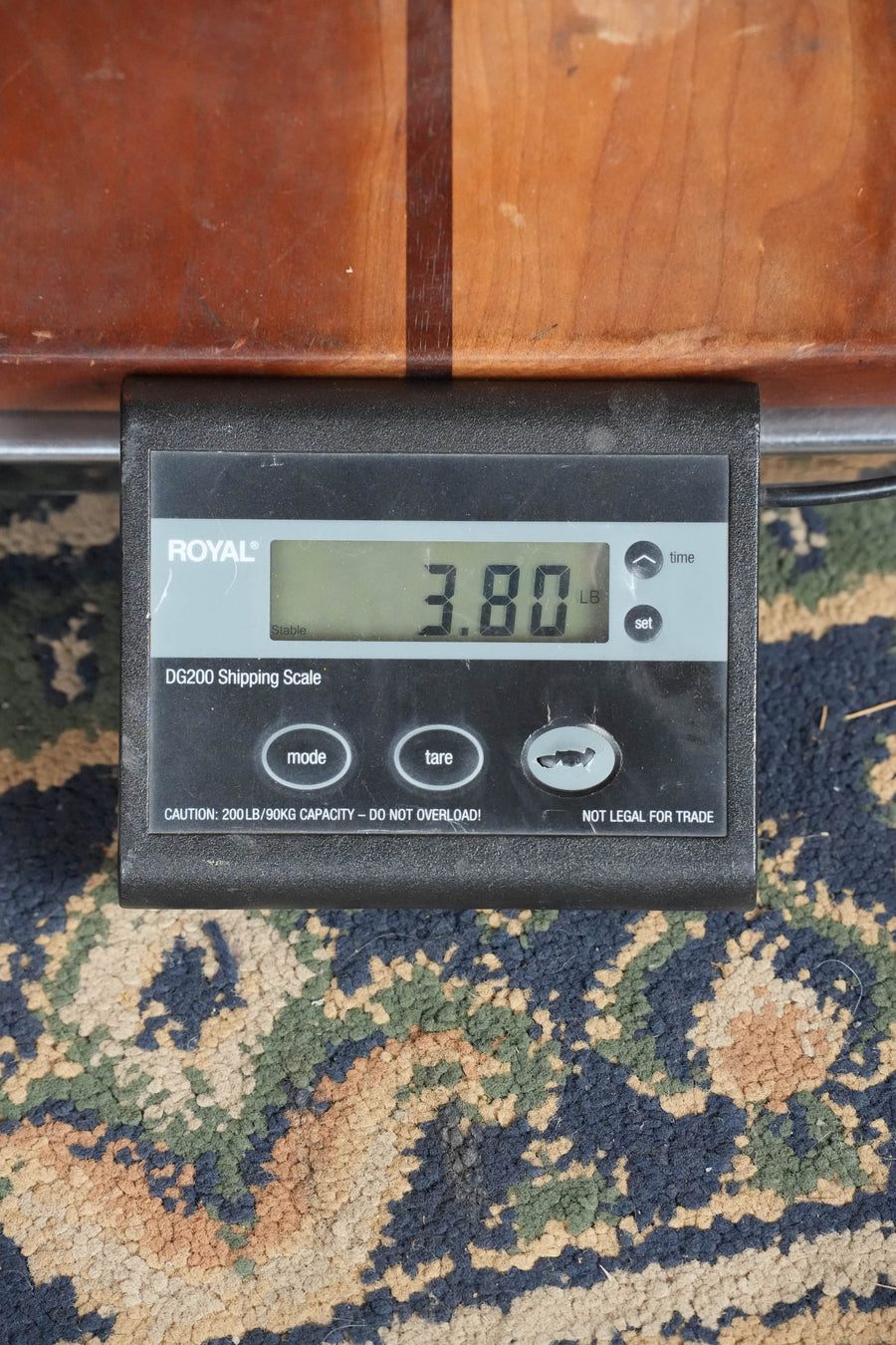 A digital shipping scale on a patterned carpet shows 3.80 pounds as the black ROYAL scale weighs the Bourgeois Country Boy Touchstone Series Sitka/Mahogany Sunburst Orchestra Model Acoustic Guitar #0252—great for fingerstyle players seeking a lightweight instrument.