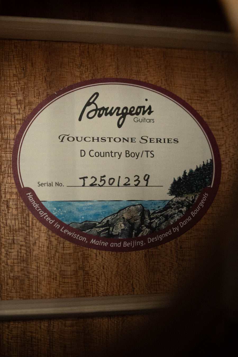 Label inside the Bourgeois Country Boy Touchstone Series Sitka/Mahogany Natural Dreadnought Acoustic Guitar #1239 reads: Bourgeois Guitars, Serial No. T2501239, handcrafted in Lewiston, Maine and Beijing. Designed by Dana Bourgeois.