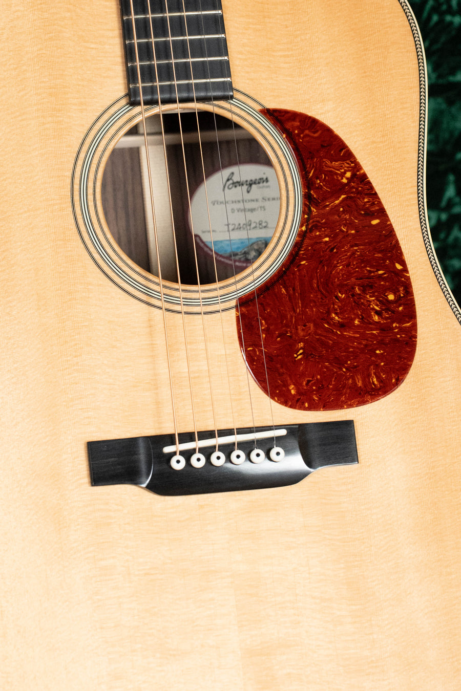 Close-up of a Bourgeois D Vintage/TS Touchstone Series Sitka/Rosewood Dreadnought Acoustic Guitar #9282 body, showing its Sitka spruce top, sound hole, rosette, tortoiseshell pickguard, bridge, and strings in a natural wood finish.