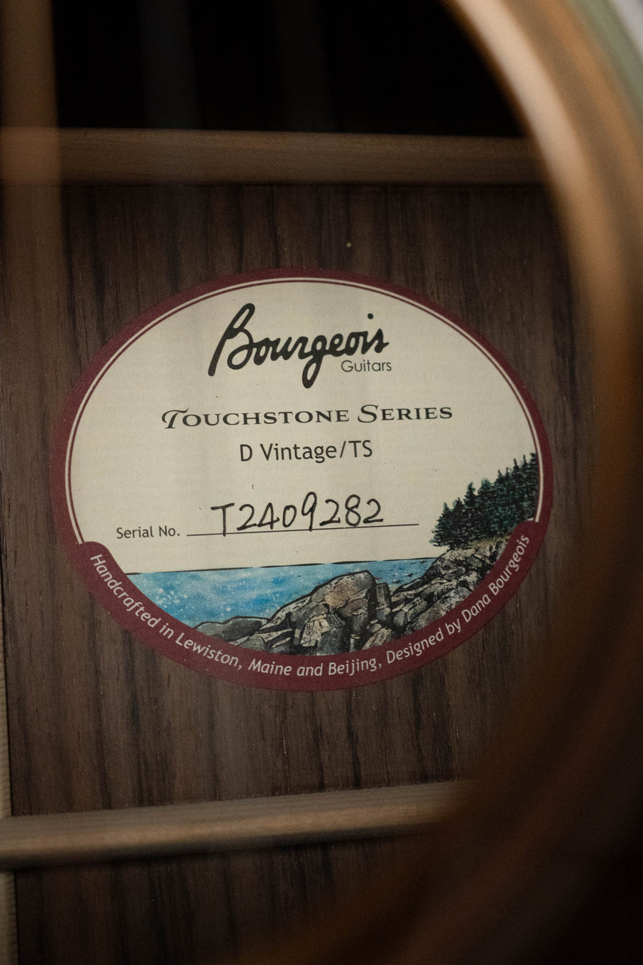 Close-up of a Bourgeois D Vintage/TS Touchstone Series Sitka/Rosewood Dreadnought Acoustic Guitar #9282 soundhole label, featuring coastal artwork and highlighting "Old-Growth Alaskan Sitka Spruce.