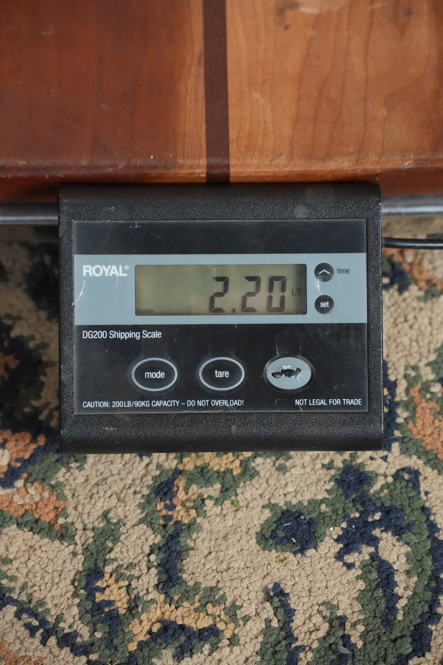 A digital shipping scale shows 2.20 pounds on a patterned carpet, with part of a Bourgeois M5-F-BT Aged-Tone Adirondack/Maple Black Top F-Style Mandolin (#3102) by Bourgeois visible above the scale.