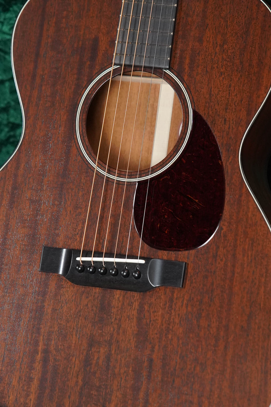 Close-up of the Bourgeois PSHT-OM-S Professional Series Hog Top All Mahogany Satin Finish Orchestra Model Acoustic Guitar #1233, showcasing its dark mahogany body, steel strings, black bridge, and fine natural wood grain craftsmanship.