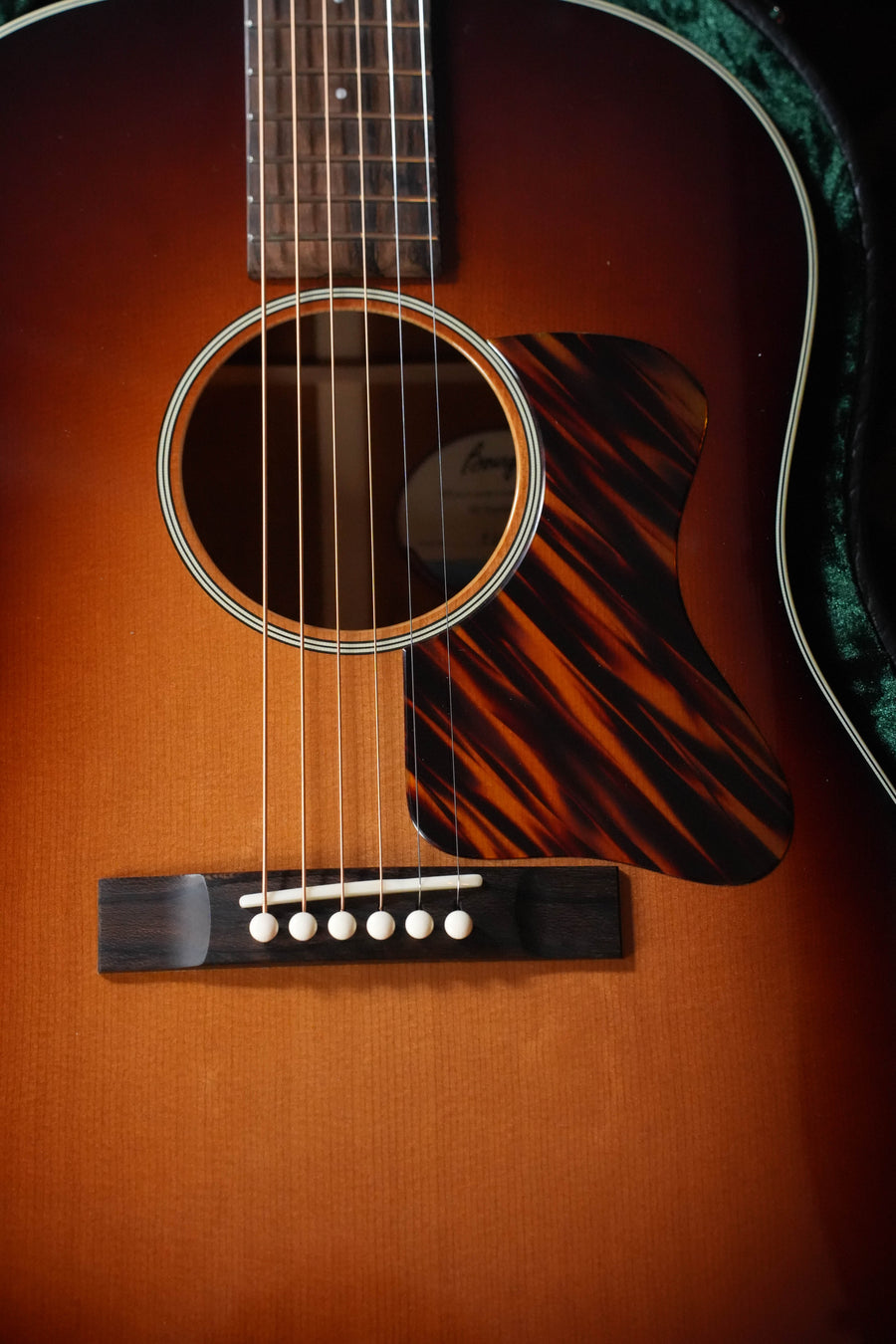 Close-up of the Bourgeois The Standard SDS/TS Touchstone Series Slope Shoulder Dreadnought Acoustic Guitar, showing its strings, bridge, sound hole, and tortoiseshell pickguard on a torrefied Sitka spruce sunburst body.