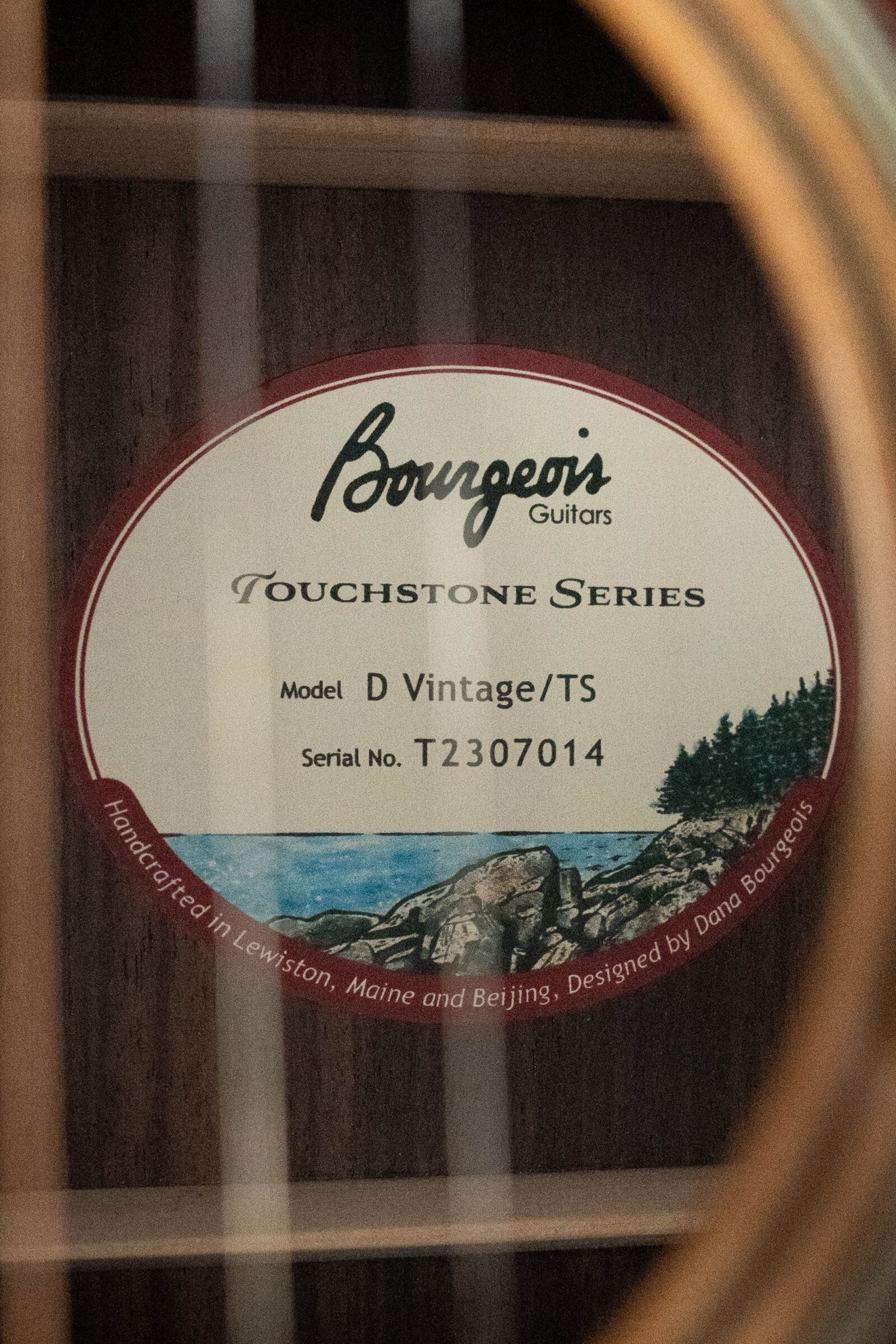 Close-up of the Bourgeois D Vintage/TS Touchstone Series Dreadnought Acoustic Guitar #7014 label, featuring a coastal illustration and crafted from Old-Growth Alaskan Sitka Spruce.