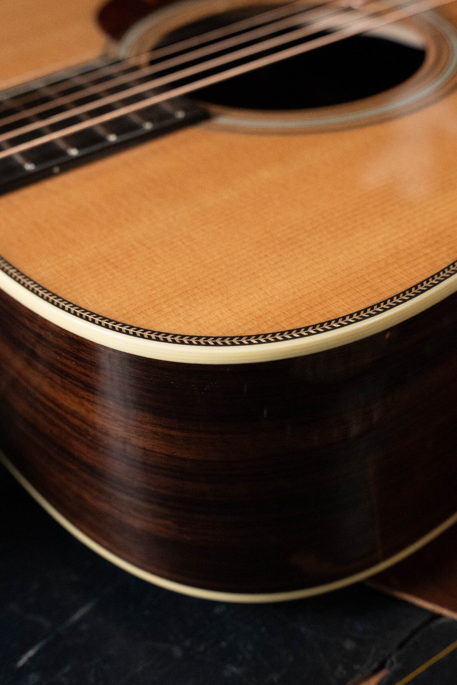 Close-up of the Bourgeois D Vintage/TS Touchstone Series Dreadnought Acoustic Guitar #7014, showing its Old-Growth Alaskan Sitka Spruce wood grain, strings, and decorative edge around the soundhole.