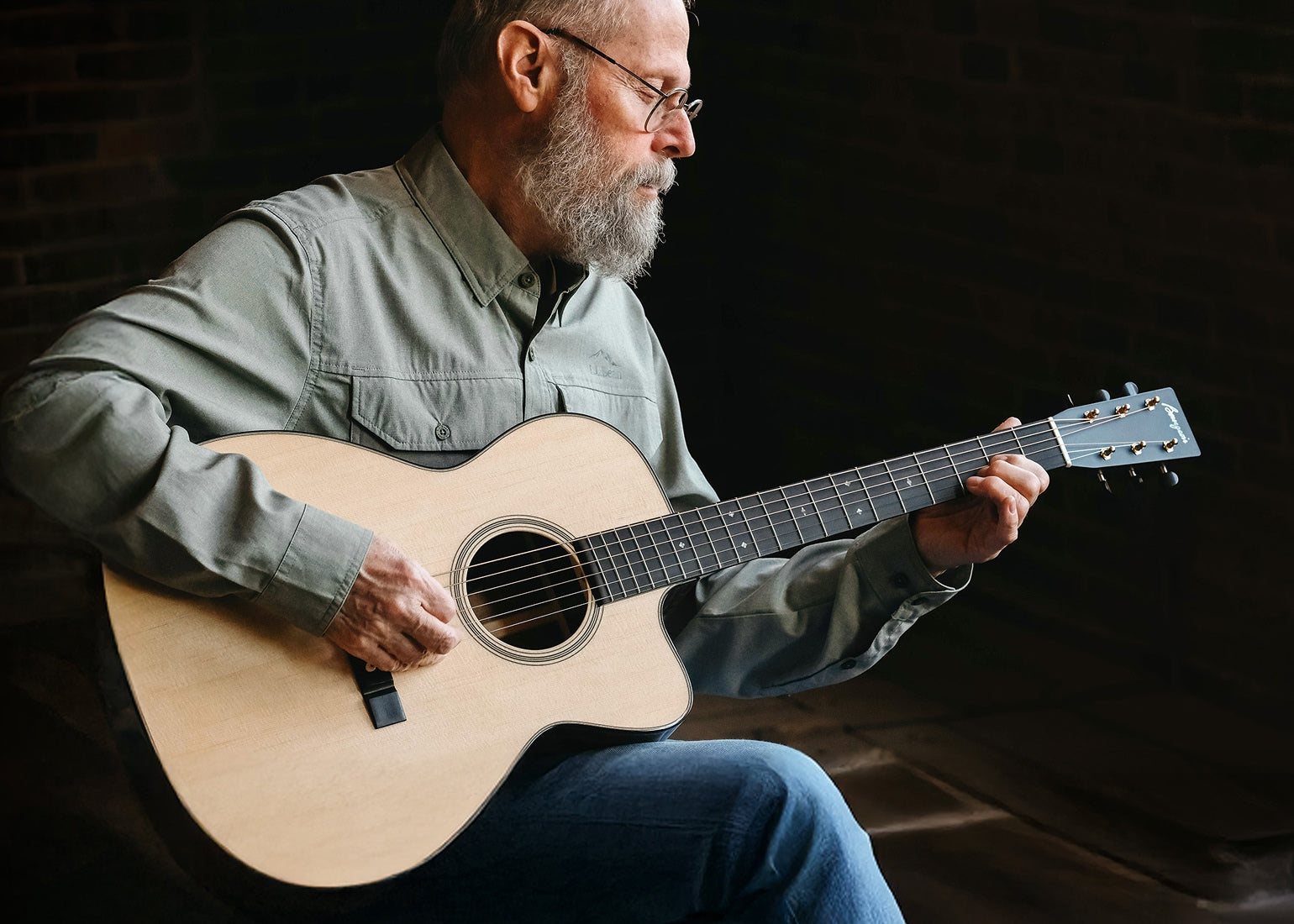 Dana Bourgeois playing a new Bourgeois Soloist/TS acoustic guitar against a dark background