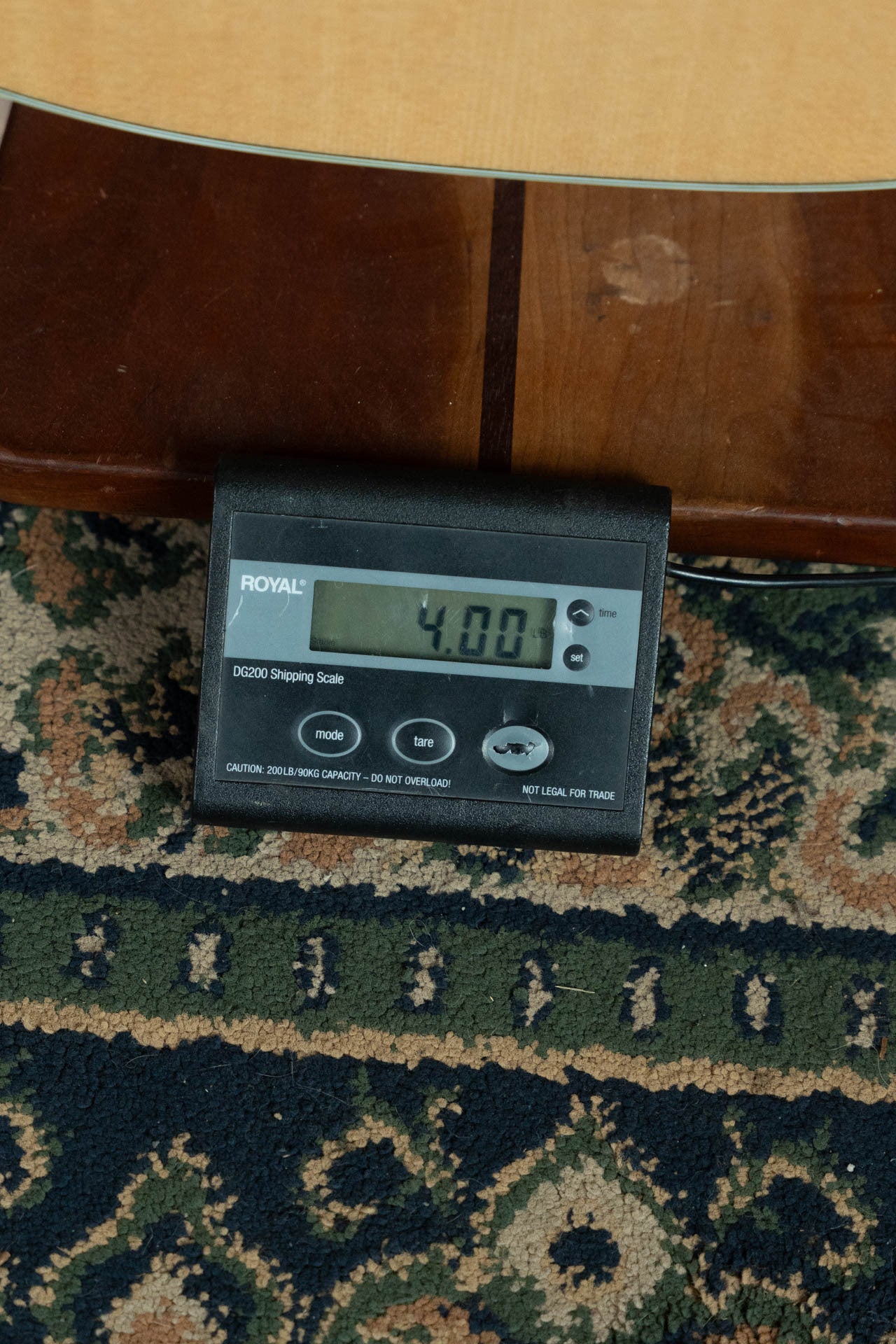 A digital shipping scale displays 4.00 pounds in front of a Boucher Guitars Bourgeois PSN-SD-S Satin Professional Series The Natural Sitka/Mahogany Slope Shoulder Dreadnought Acoustic Guitar #1174 on a patterned rug.