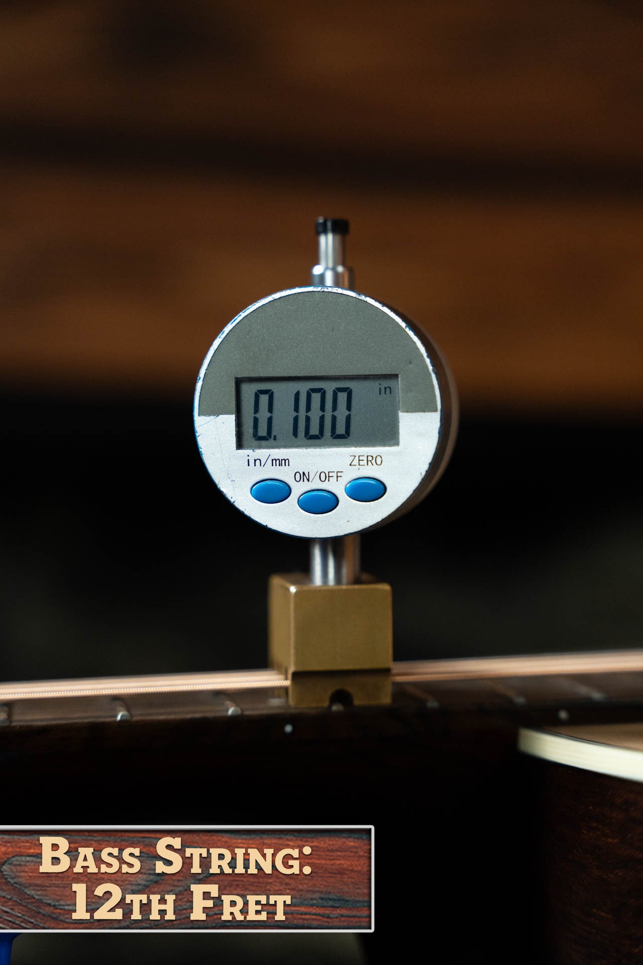A digital gauge shows the bass string height above the 12th fret as 0.100 inches on a Boucher Guitars Bourgeois PSN-SD-S Satin Professional Series The Natural Sitka/Mahogany Slope Shoulder Dreadnought Acoustic Guitar #1174. Label: Bass String: 12th Fret.