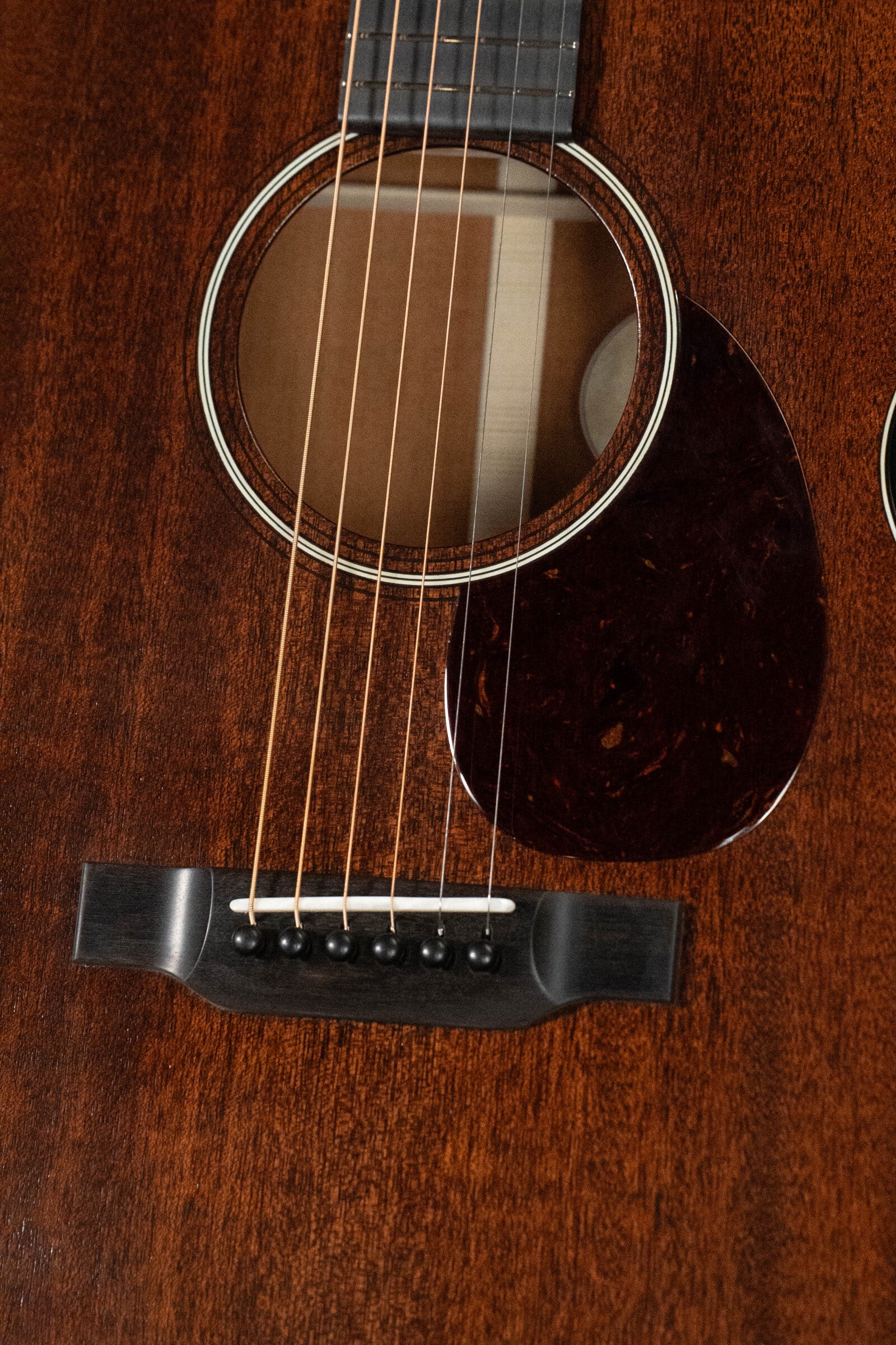 Close-up of the Bourgeois Professional Series Hog Top All Mahogany OM Acoustic Guitar #1208, showcasing its Orchestra Model shape, soundhole, strings, rich mahogany finish, bridge, and pickguard.