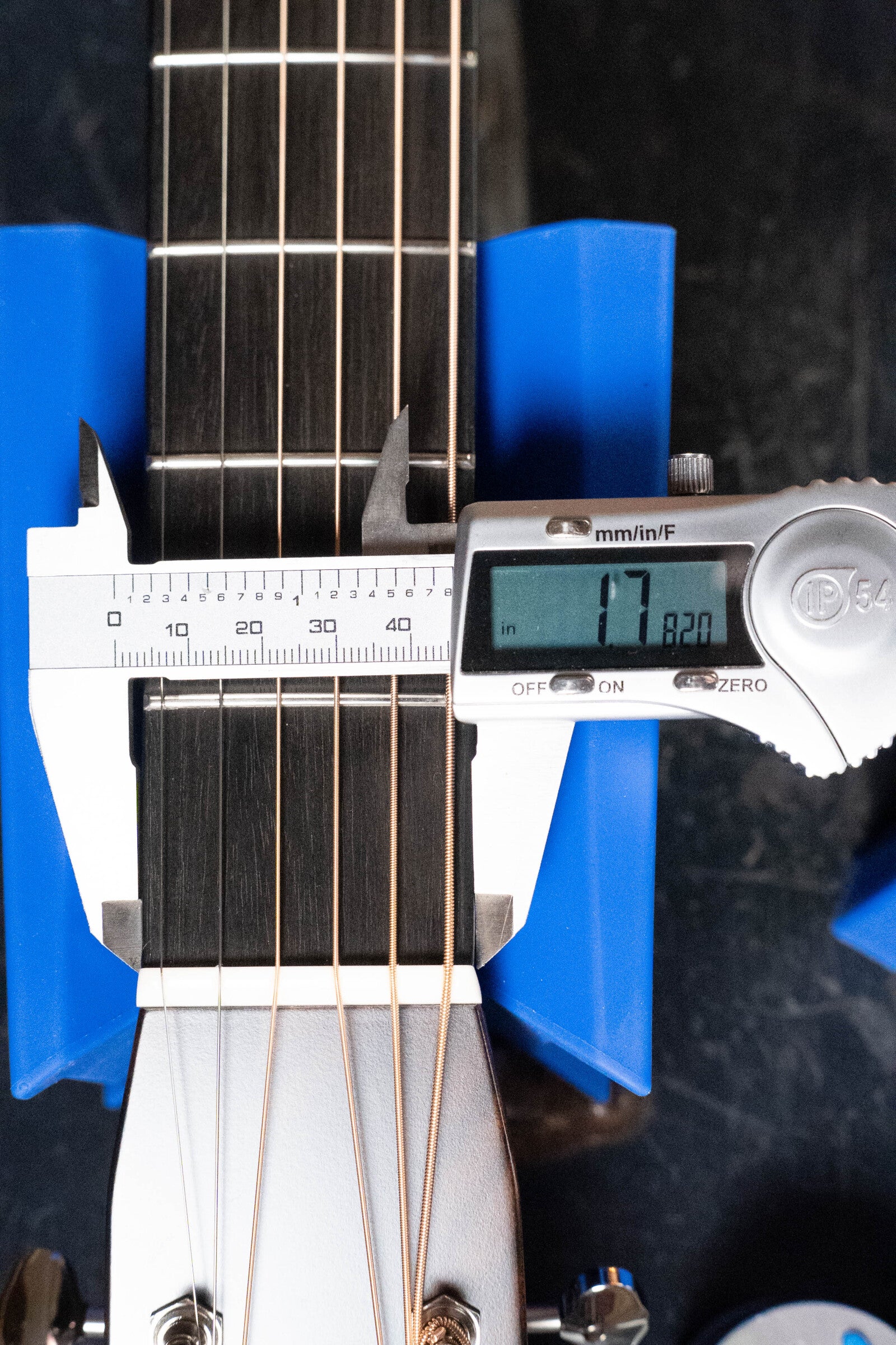A digital caliper measures the nut width of a Bourgeois Professional Series Hog Top All Mahogany OM Acoustic Guitar #1208, showing 1.78 inches on the display, while blue supports hold the instrument in place.
