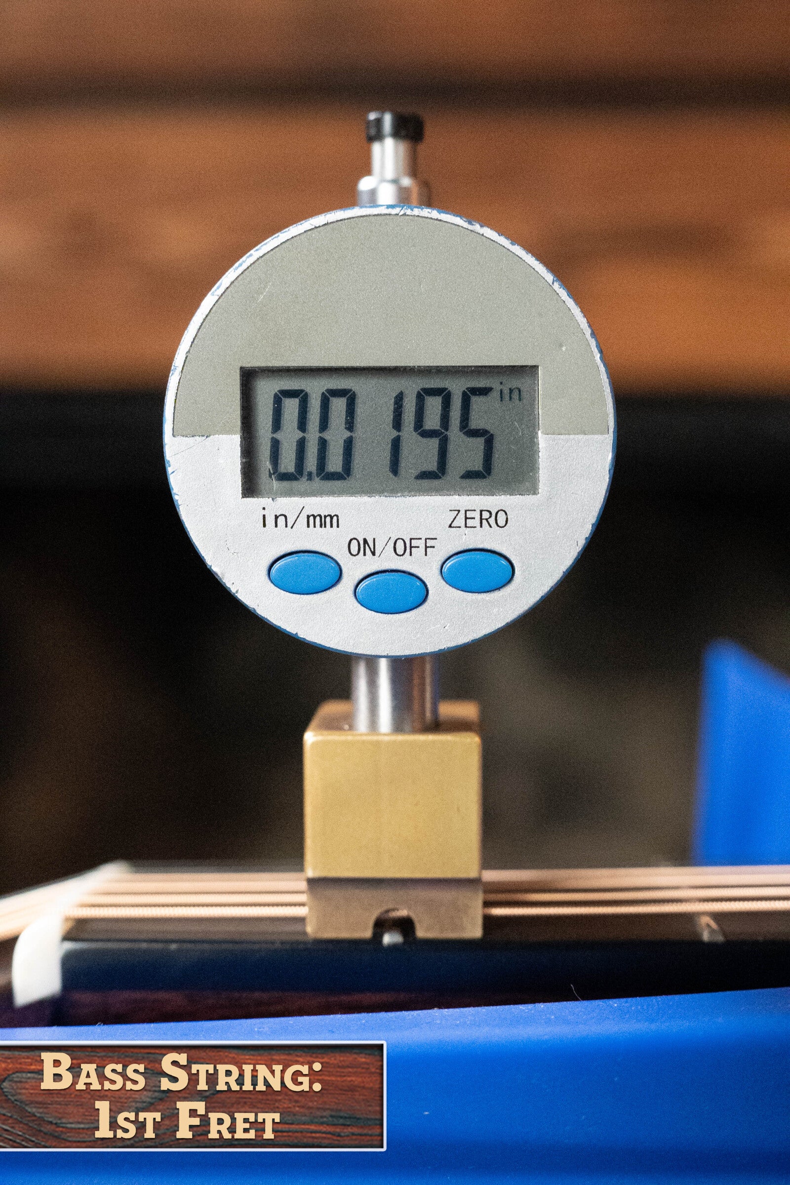 A digital gauge reads 0.0195 inches above a bass guitar string at the 1st fret, labeled "Bass String: 1st Fret," similar to precise setups on the Bourgeois Professional Series Hog Top All Mahogany OM Acoustic Guitar #1208 by Bourgeois.