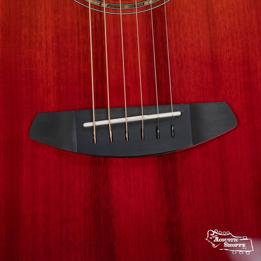 Close-up of the Breedlove Limited Oregon Series All Myrtlewood Thinline Hot Rod Concert CE Guitar's bridge and strings, highlighting its wood grain. Six strings are anchored on the dark bridge; “Acoustic Shoppe” logo in bottom right.