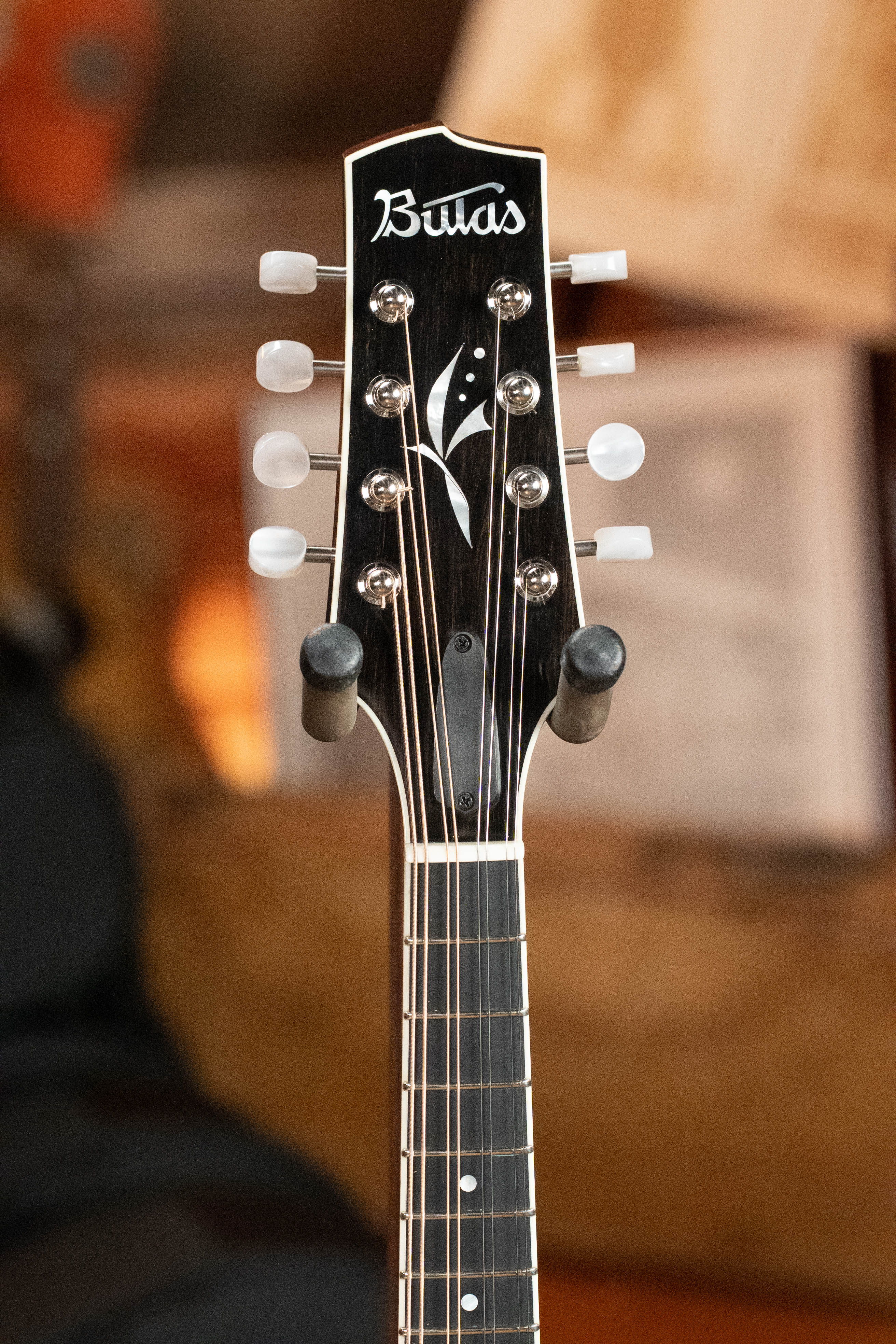 Close-up of the headstock of a Bulas A-Style Mandolin, featuring tuning pegs, a Cremona sunburst finish with white inlays, and the Bulas brand on top—crafted with Carpathian spruce for exceptional sound quality.