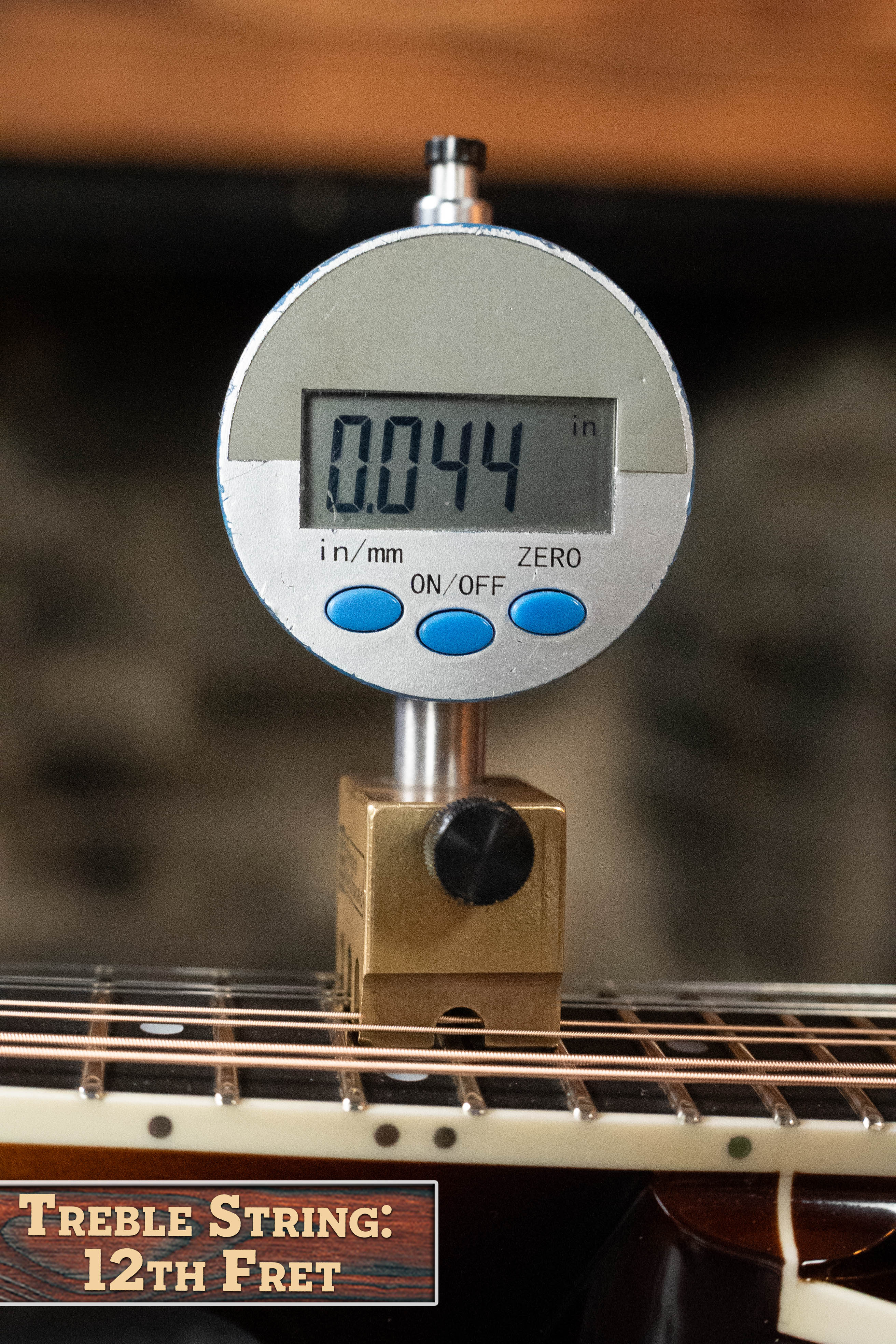 A Bulas digital gauge reads 0.044 inches while measuring treble string height at the 12th fret of a Bulas Carpathian Spruce/Curly Maple Cremona Sunburst A-Style Mandolin #8129. The brass holder is labeled "Treble String: 12th Fret.