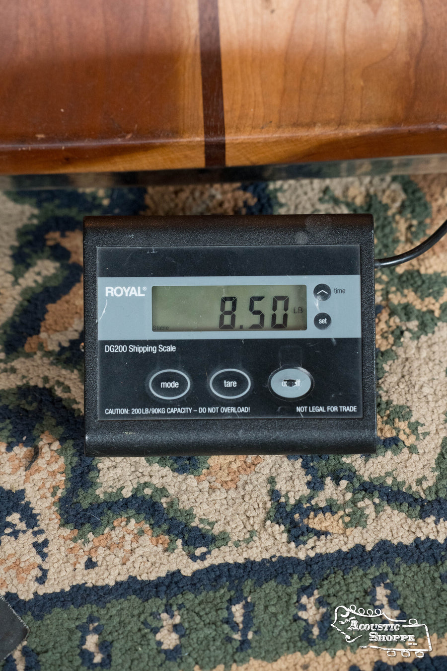 A Bulas 5 String Resonator Banjo #0767 by Bulas weighs 8.50 pounds on a ROYAL DG200 shipping scale, shown on patterned carpet beside a wooden surface—ideal for precise banjo weighing.