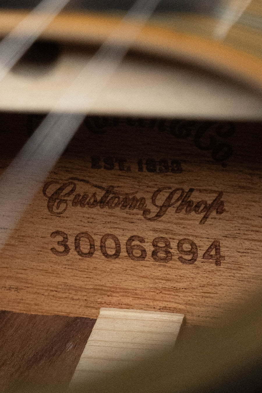 Close-up of the Martin & Co. Custom Shop OOO-28 Style "Wild Grain" Auditorium Acoustic Guitar #6894's interior, revealing the Martin label and serial number engraved on its East Indian rosewood body.