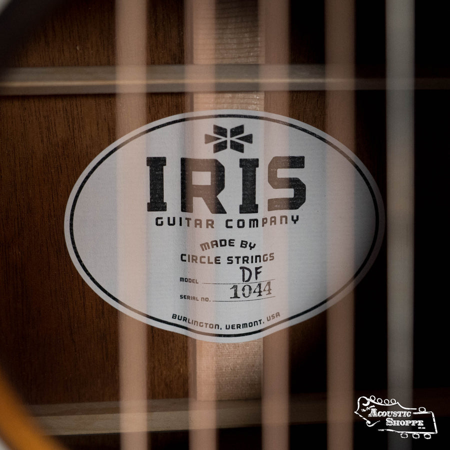 Close-up of an Iris Guitars IRIS DF *Custom* Guild Sitka/Old Mahogany Burst Slope Shoulder Dreadnought Guitar #1044 inner label—Burlington, VT origins—seen behind the strings with the Acoustic Shoppe logo in the corner.