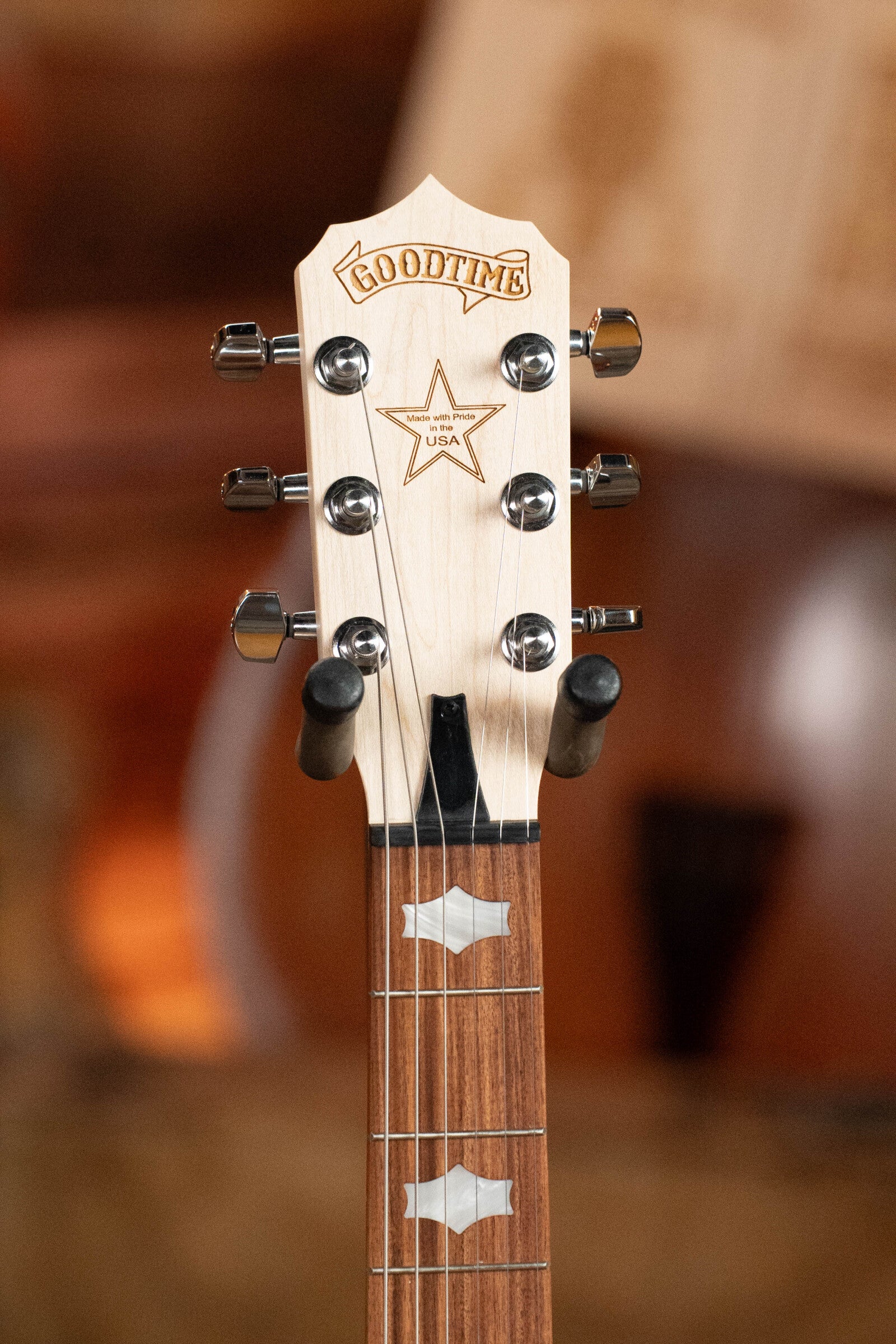 Close-up of a Deering Banjos Goodtime Six-R 6-String Resonator Banjo headstock, featuring light wood, star inlay, USA marking, tuning pegs, and fretboard—ideal for Kavanjo pickup fans. Blurred background. Model #2520.